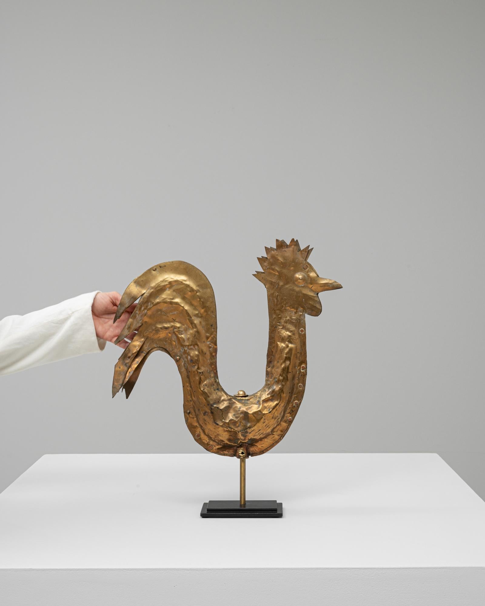 Questo gallo in ottone francese del XIX secolo è un affascinante pezzo decorativo che riflette il carattere giocoso e simbolico spesso presente nell'arte rurale francese. Realizzato in ottone lavorato a mano, presenta una silhouette stilizzata con