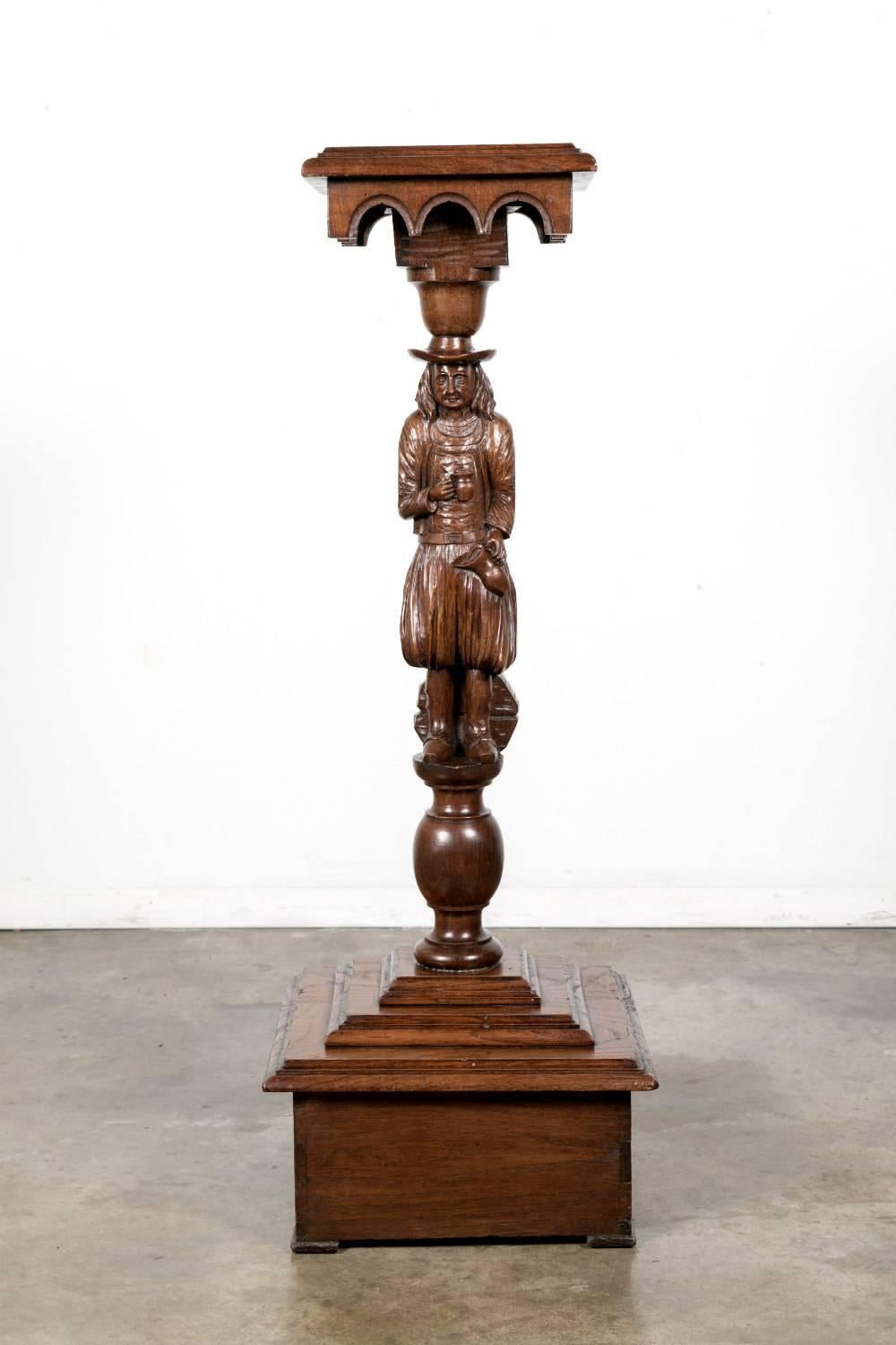 A charming 19th century French plant stand hand-carved in solid chestnut of a Breton man in traditional dress and hat pouring himself another pitcher of wine. In classic Breton style, it will add a Country French touch to any space. 

Antique