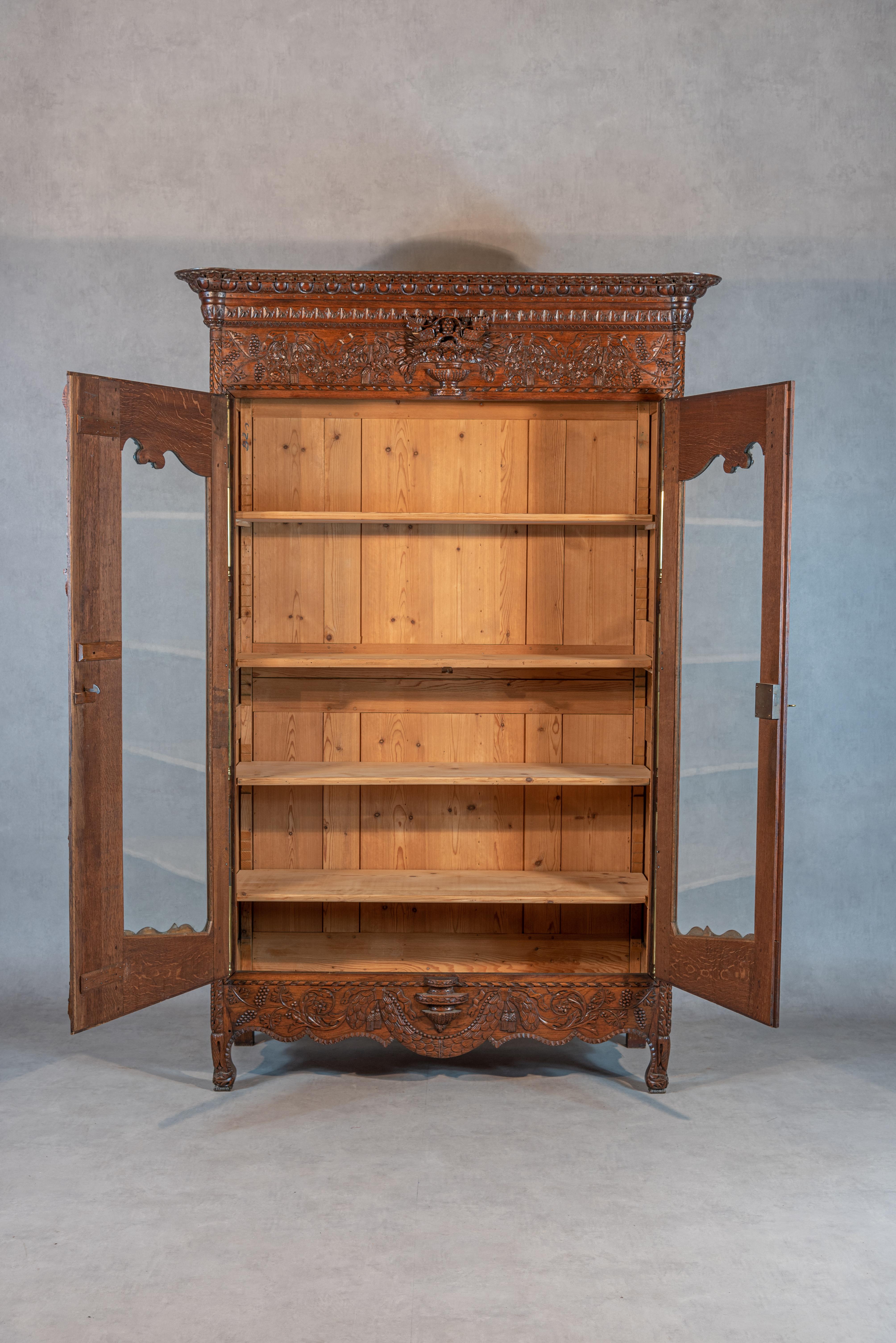 This exquisite 19th-century French Bridal Armoire with glass doors is a true masterpiece. Crafted from solid oak, this piece of furniture boasts impressive woodwork that is sure to leave any onlooker in awe. The armoire features sculpted ornaments