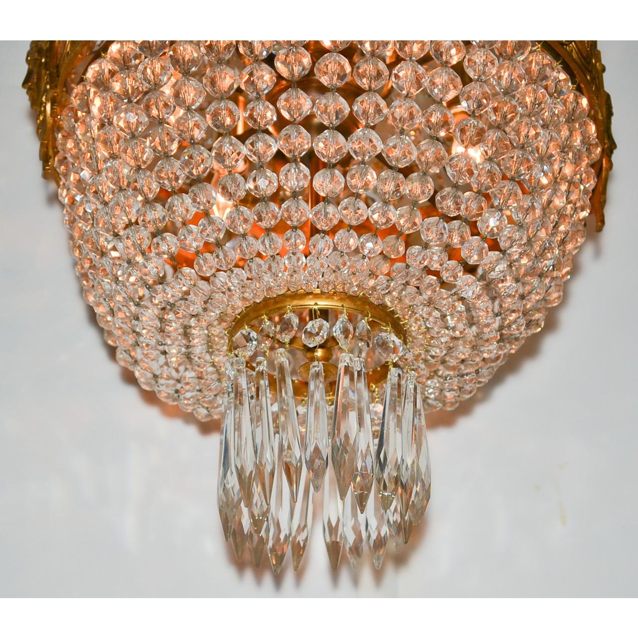 Beautiful tall and slender 19th century French basket form chandelier. The gilt bronze acanthus leaf canopy elegantly draped with multiple strands of faceted bead crystals atop a central gold gilded bronze band with highly detailed caryatid masques