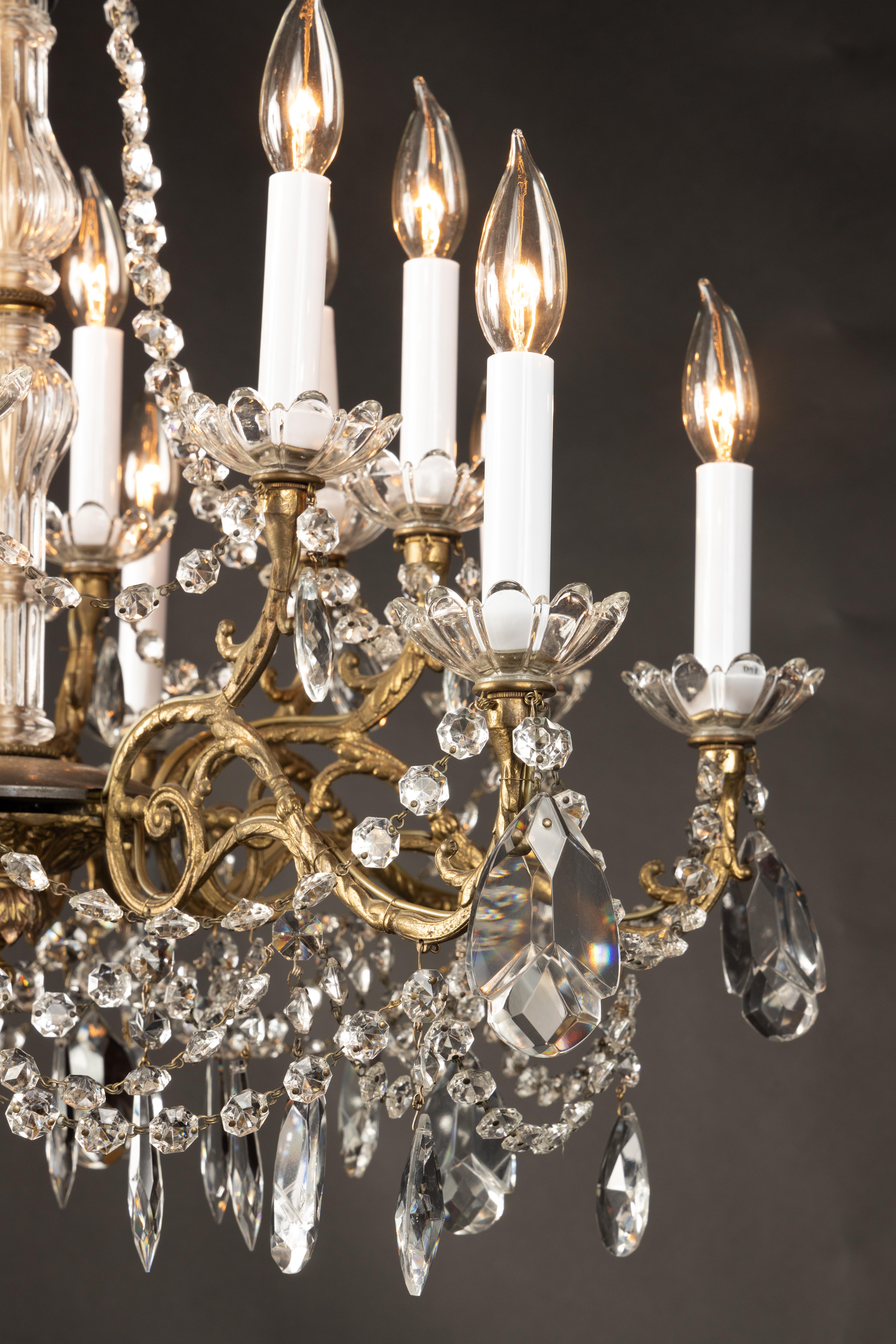 This elegant Napoleon III two tier chandelier is made of bronze and draped with ropes of octagon-cut crystals, pear-shaped teardrop crystals, and crystal spears. The French antique fixture dates back to the late 19th century and plays host to a