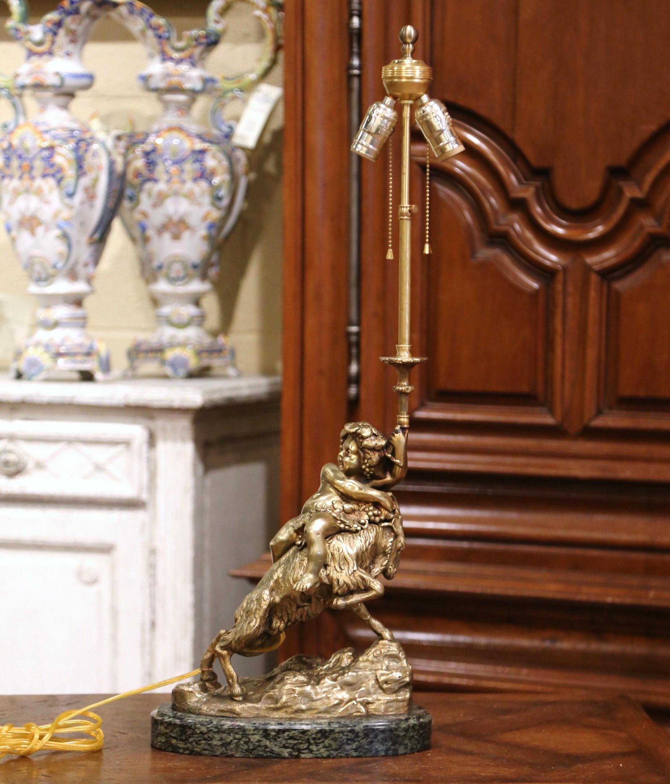Decorate an office or study with this elegant antique figural lamp. Crafted in France circa 1870 and standing on an oval green marble base, the bronze doré composition features a cheerful young Bacchus figure sitting on a ram, decorated with grape