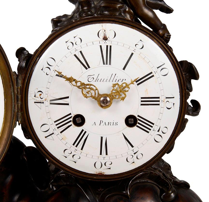 An enchanting 19th Century French, Louis XVI style patinated bronze and gilded ormolu mantel clock, having a cherub with bow above the white enamel clock face, Roman numerals, an eight day duration movement that chimes on the hour and half