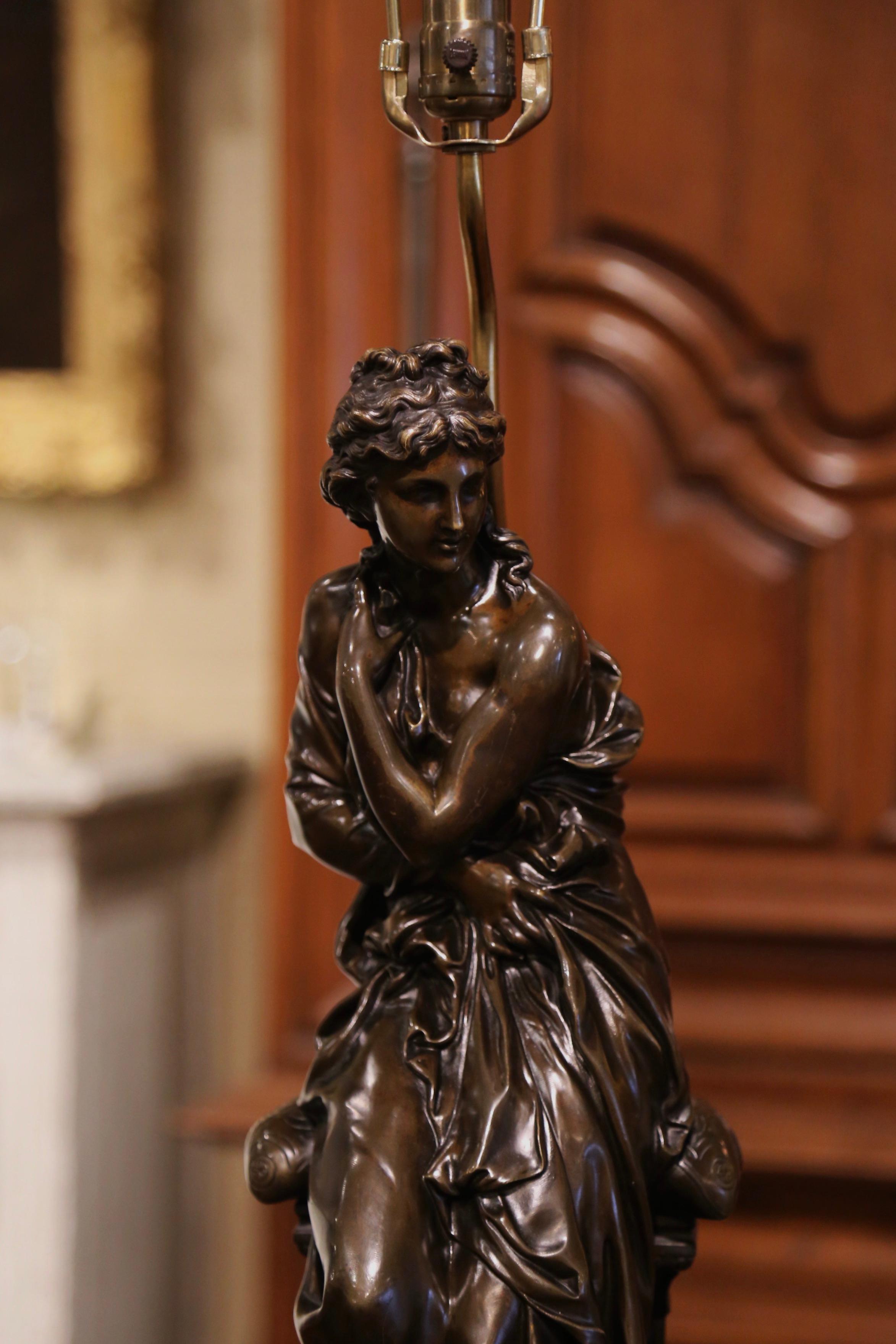 Crafted in France, circa 1860, the antique bronze lamp stands on a marble plinth base with rounded cut corners, and features a classical female figure. The bronze sculpture is signed by French artist Henry Etienne Dumaige; it has been wired and