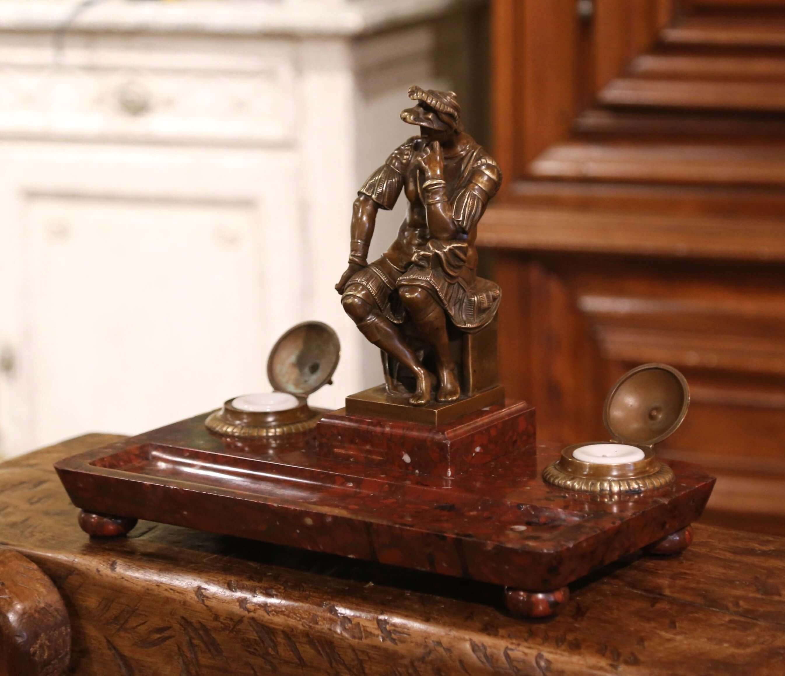 Decorate your office desk with this large Empire style inkwell. Created in France circa 1870 and rectangular in shape, the inkwell features a bronze Roman soldier in the center sitting on a stool. On either side of the figure, are two bronze