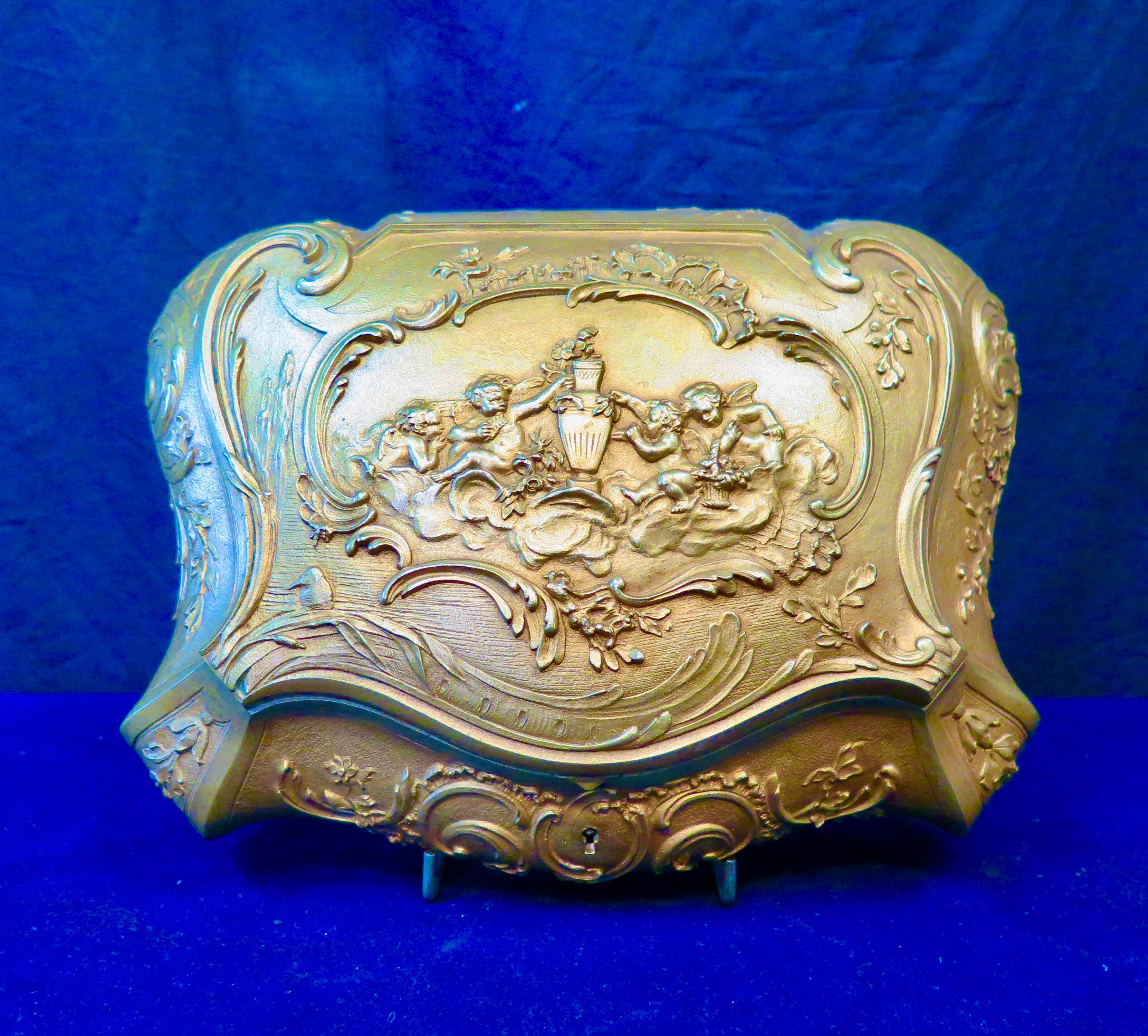 This sturdy 19th century French dore’ bronze hinged ladies jewel box is designed with wonderfully detailed panels. Additionally, a beautifully designed lid cover is dominated with a sculpted motif of multiple cherubs, amid clouds, positioned around