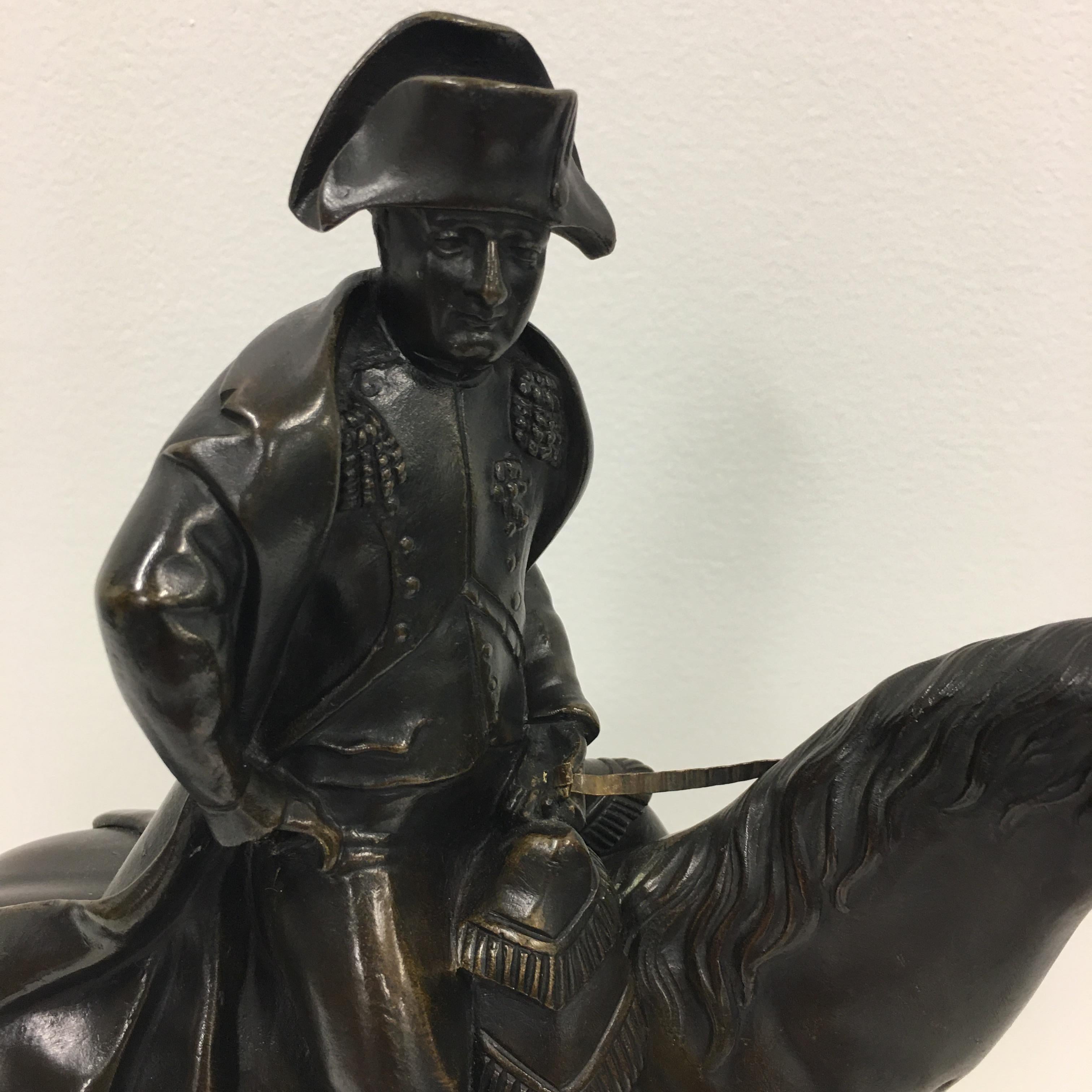 A 19th. century French bronze of Napoleon Bonaparte mounted on his horse. He is wearing A bicorn hat, breeches, vest and A long coat seated on a fringed saddle. The bronze is mounted above a rectangular white marble base. Signed :Garnier ( J.