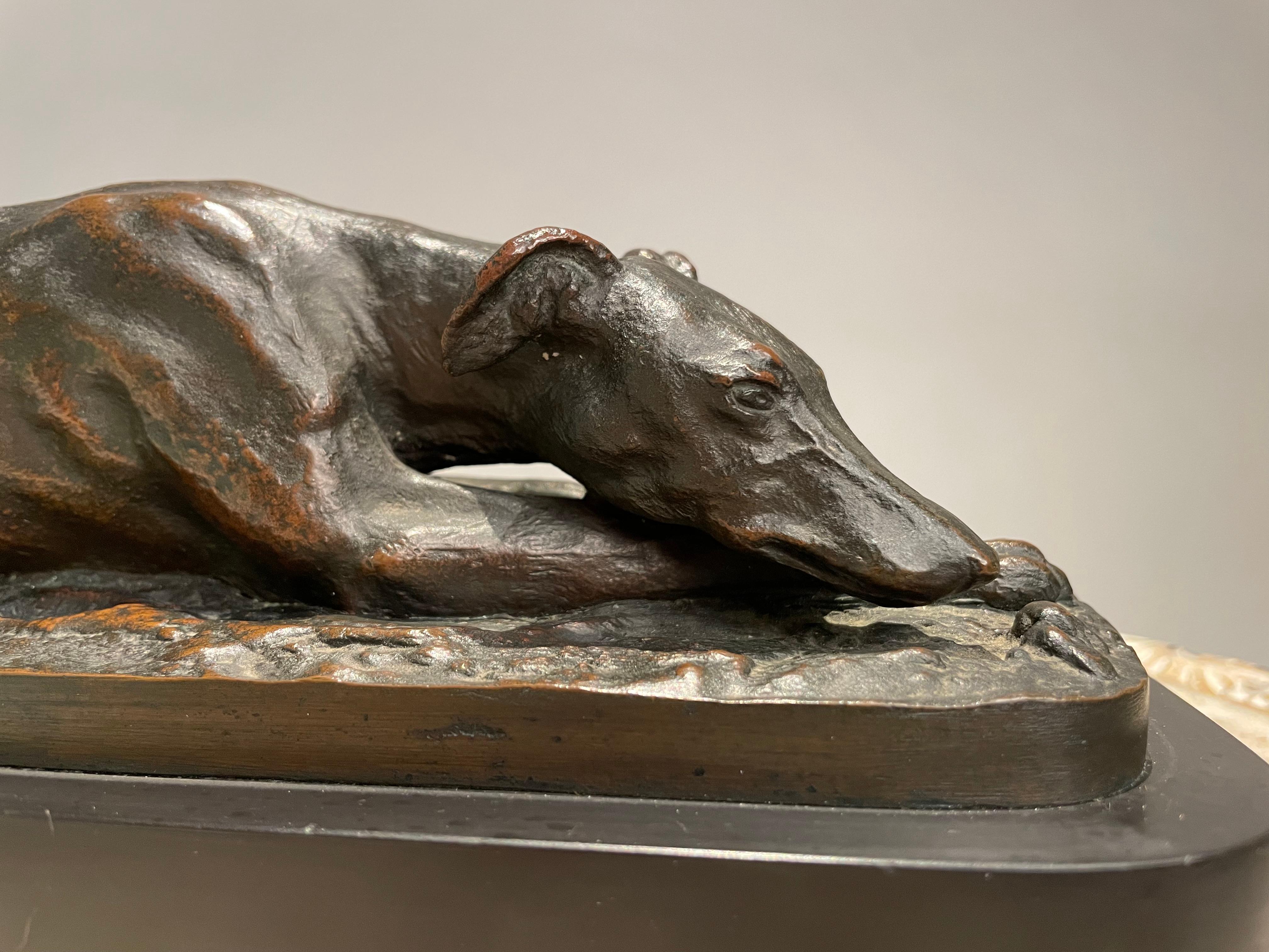 Very sensitive rendering of a greyhound at rest with a rich dark brown patina with lighter highlights showing through. The dog is shown reclining with one paw turned up, a detail I find endearing as a dog owner, my border collie does this too!