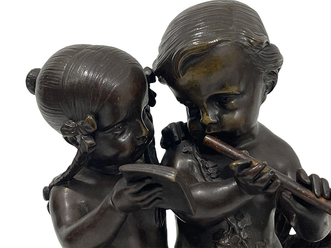 19th Century French bronze sculpture of children playing music

19th Century French bronze statue of a girl and a boy playing the flute. The girl with a braid and flowers in her hair is holding a book in front of the boy who is playing the flute,
