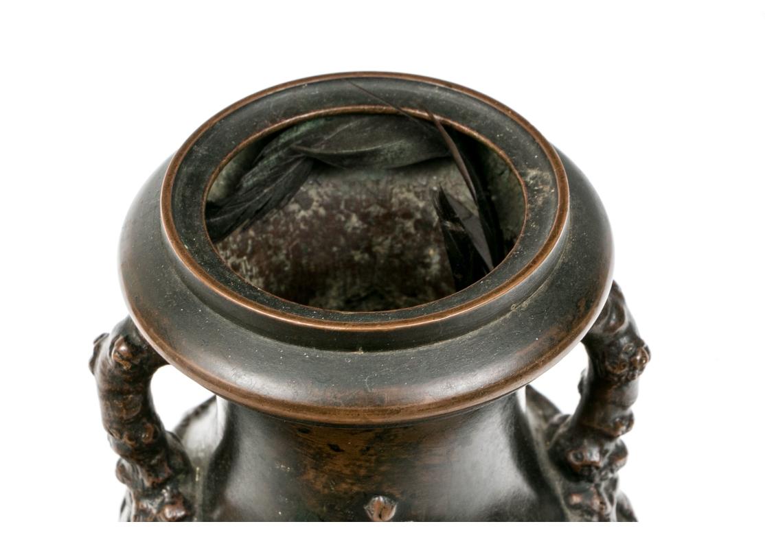 Vaso in bronzo francese del XIX secolo patinato e decorato con fiori di ciliegio e manici a forma di ramo. Il vaso a forma di balaustro con una base quadrata forata sormontata da una ciotola con piede rotondo. La ciotola con quattro grappoli di