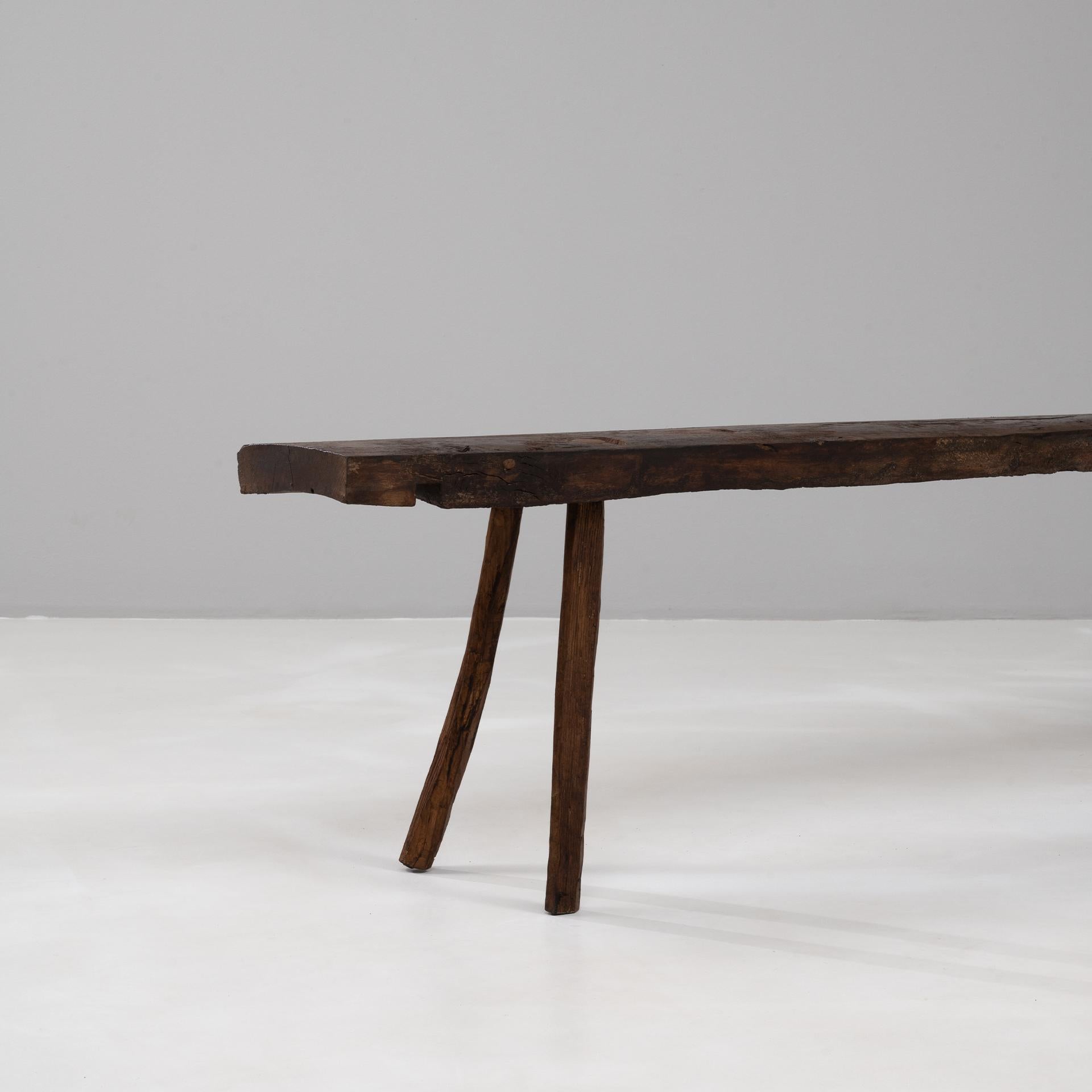 Questa panca francese brutalista del XIX secolo è un esempio di artigianato grezzo e di autenticità rustica. Ricavata a mano dal legno massiccio, presenta una seduta spessa e irregolare sostenuta da quattro robuste gambe dalla forma naturalmente