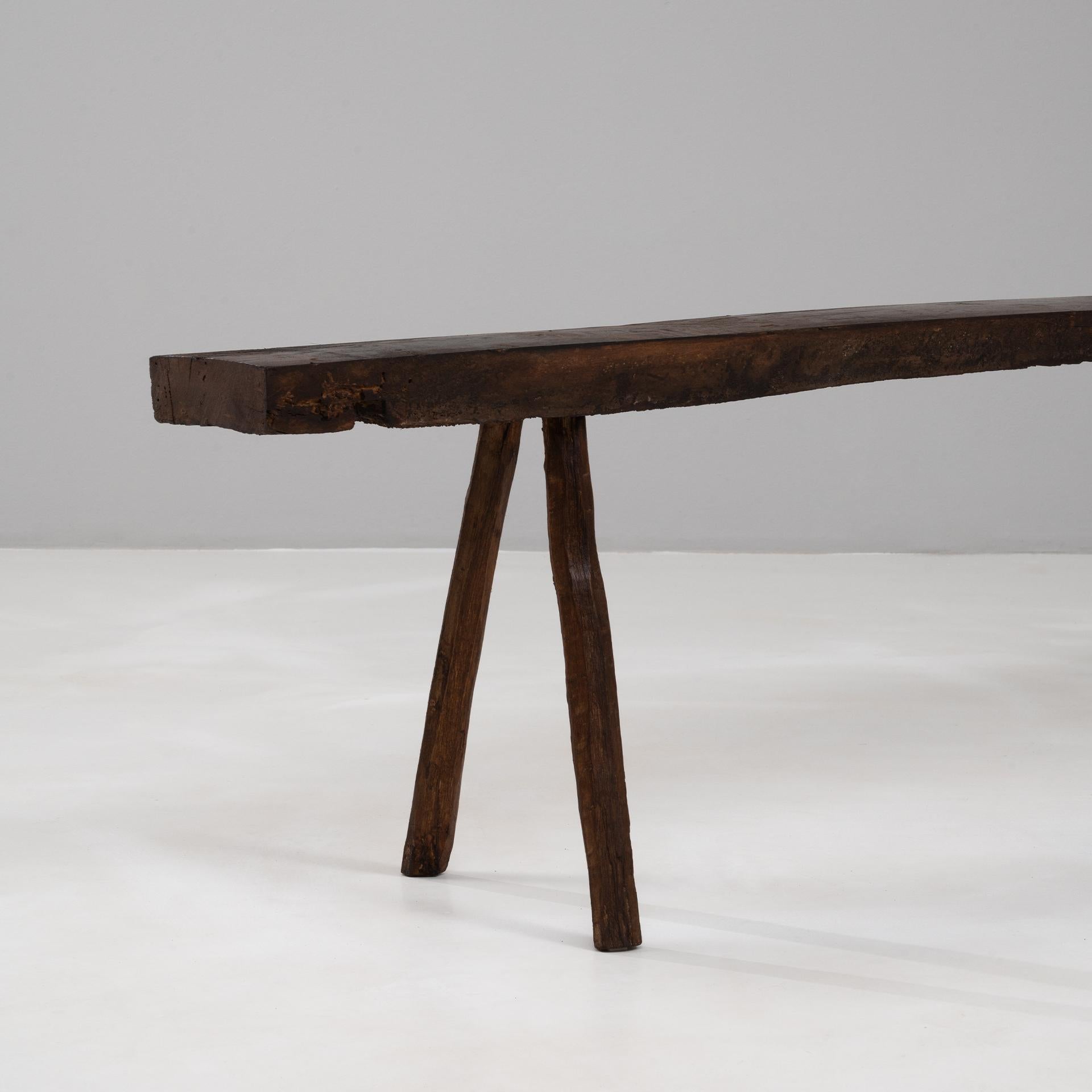 Questa panca francese brutalista del XIX secolo è un esempio di artigianato grezzo e di autenticità rustica. Ricavata a mano dal legno massiccio, presenta una seduta spessa e irregolare sostenuta da quattro robuste gambe dalla forma naturalmente
