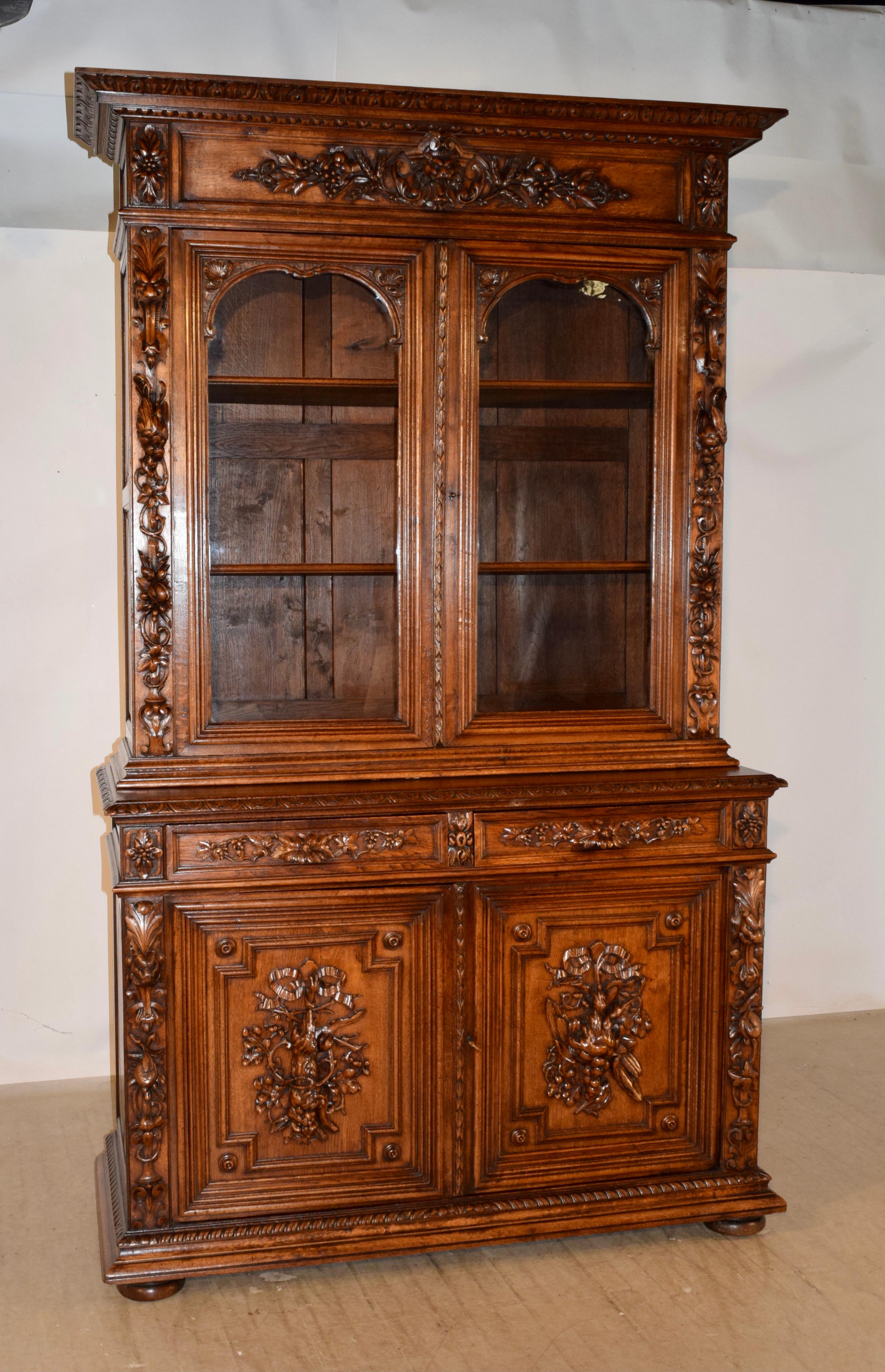 Exceptionally well-carved 19th century oak buffet deux corps from France. This two-piece cabinet features a wonderful hand carved decorated crown over a wonderful glazed door cabinet with the original glass doors. The sides of the cabinet have