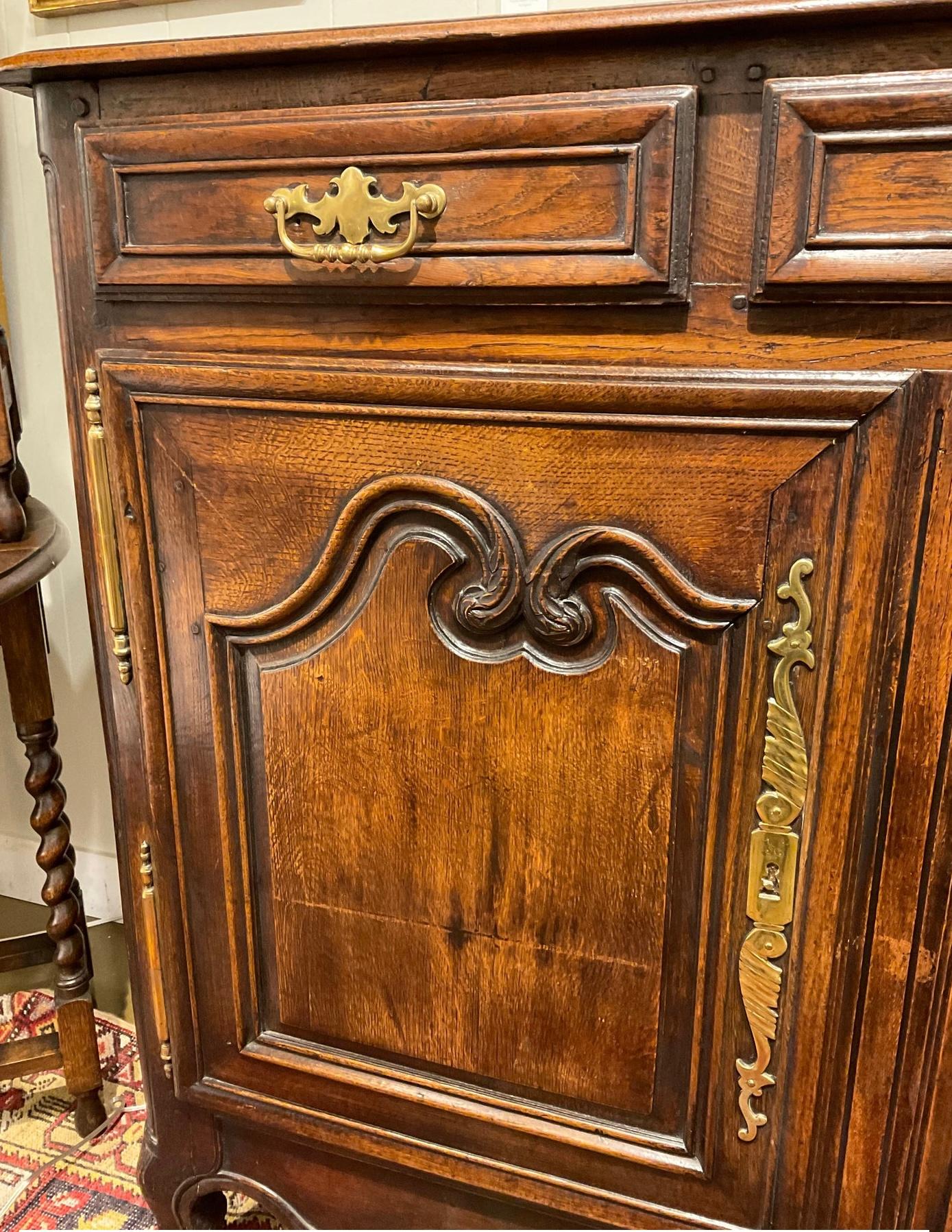 This is a gorgeous 19th century French Server! This piece has an old-world style with dark, glossy wood and ornate gold hinges, pulls and keyholes, as well as a curved, carved design on the bottom of the piece.