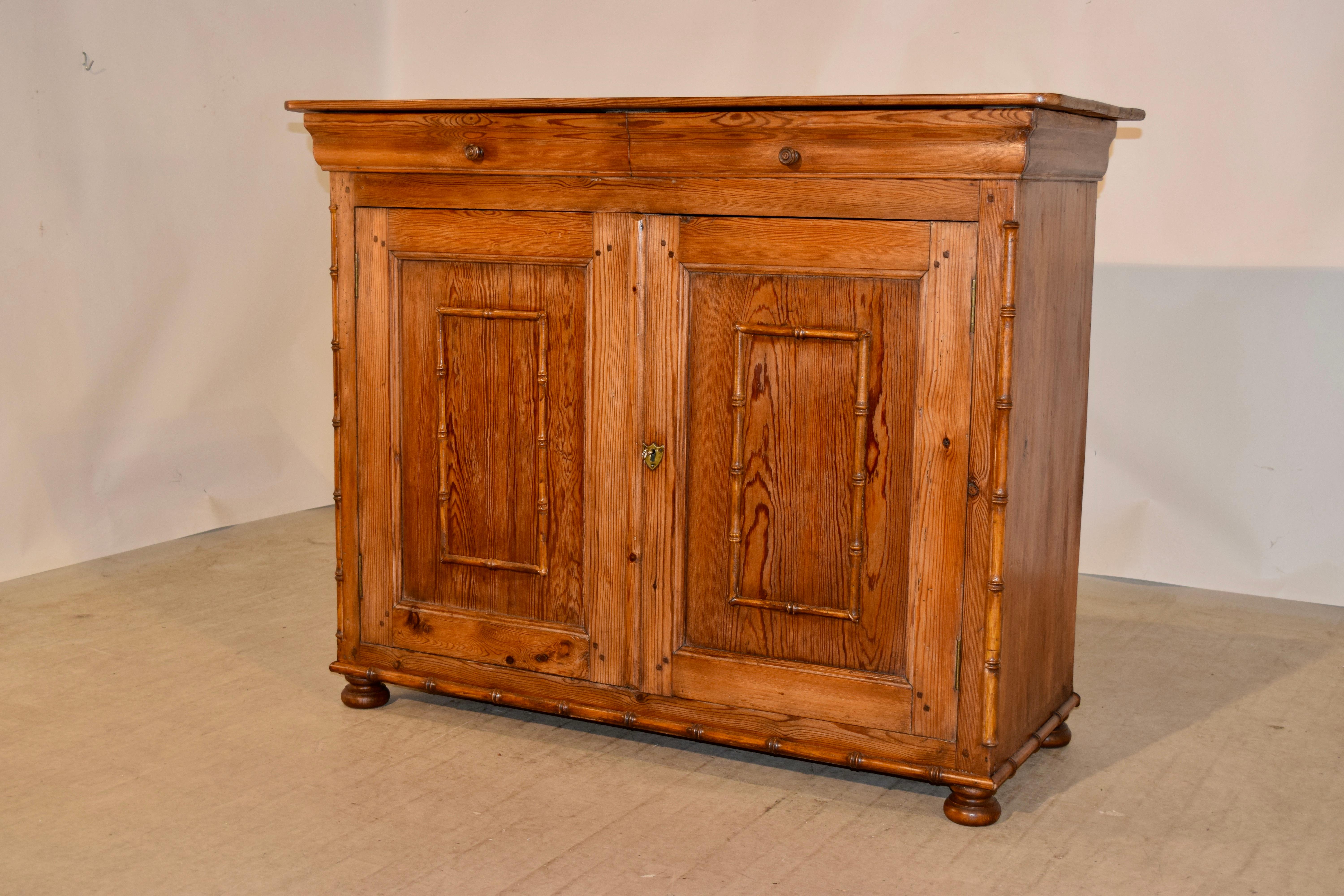 19th century French buffet in the Louis Philippe style made from pine. The top is wonderfully grained and follows down to two drawers over two doors which open to reveal storage. The piece is decorated with faux bamboo turned moldings for a warm