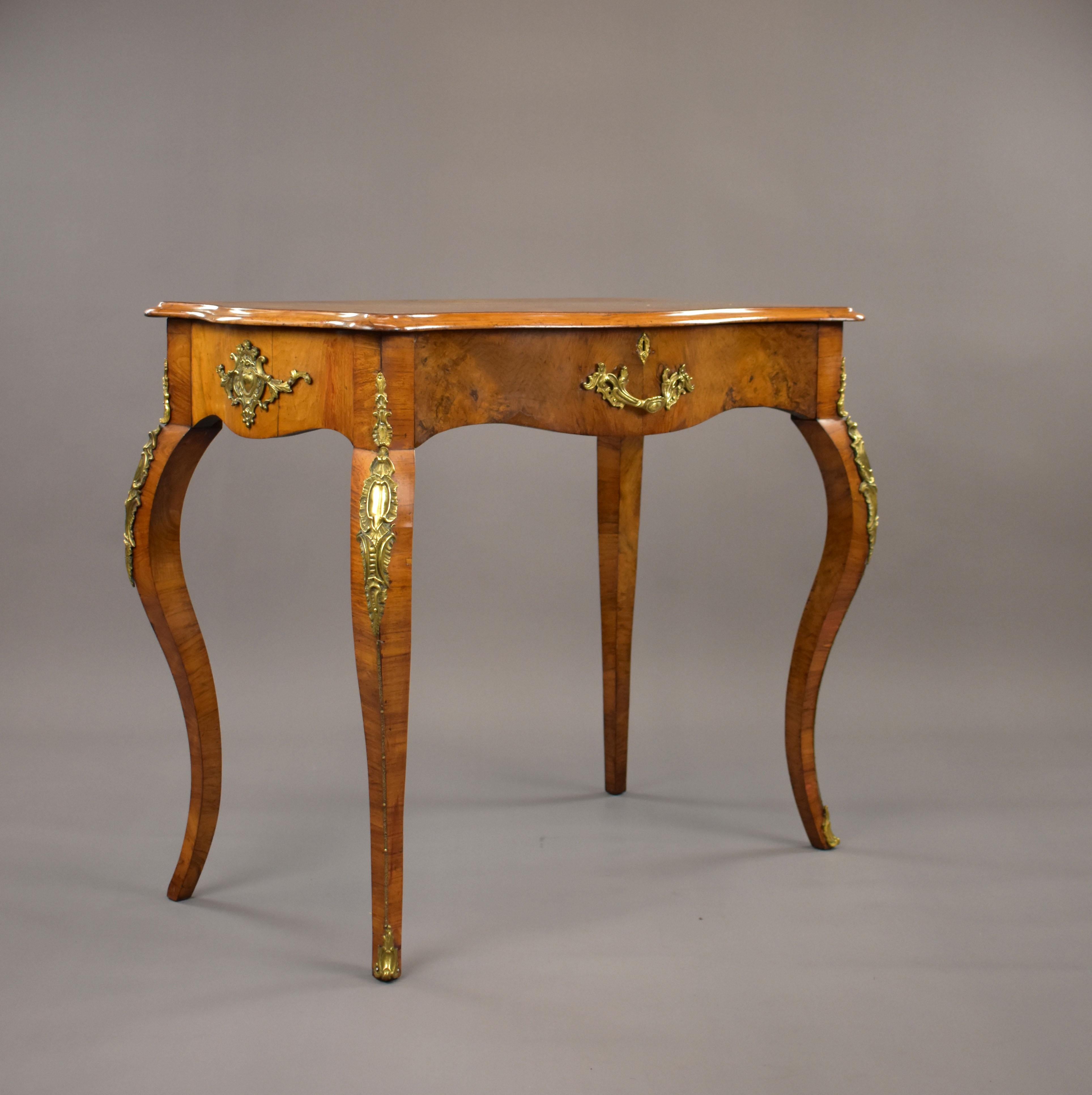 For sale is a 19th century French burr walnut writing table, having a single drawer, standing on elegantly shaped legs, the front two with decorative ormolu mounts. The table is in good condition, showing minor signs of wear commensurate with age