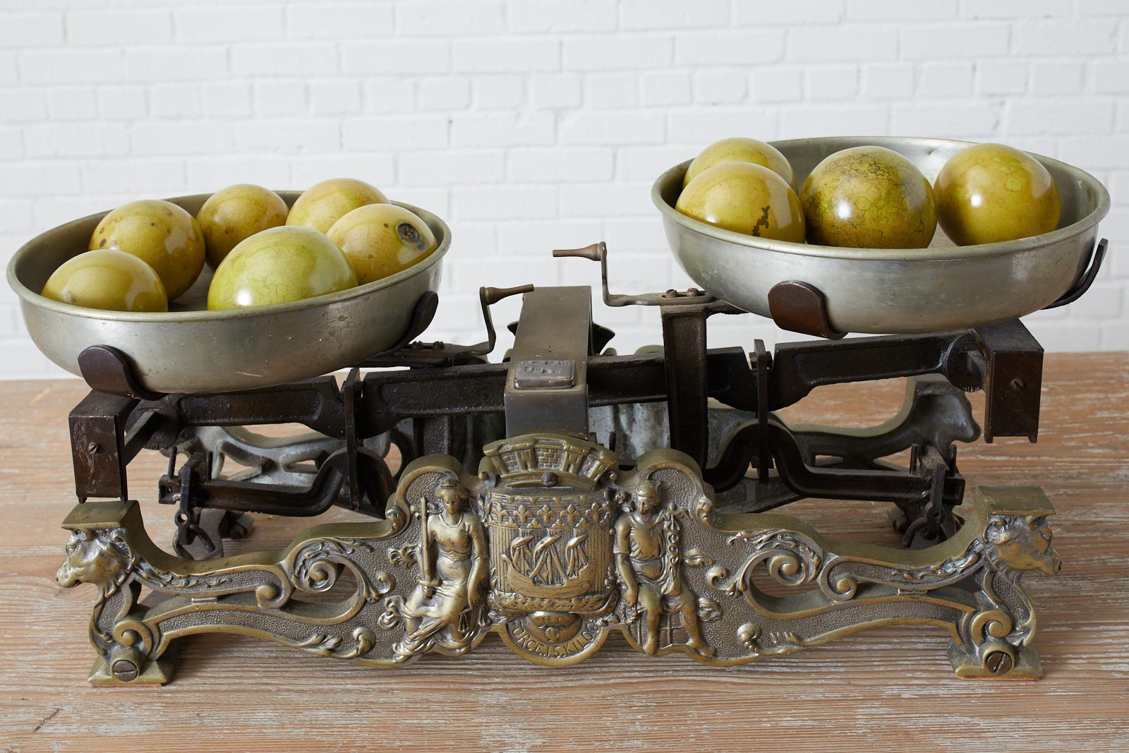Iron and brass late 19th century French butcher or merchants scale with silver metal hand formed bowls. The large scale has impressive neoclassical motif Greek figures of brass on the front center with cows heads on each end. Heavy iron frame with
