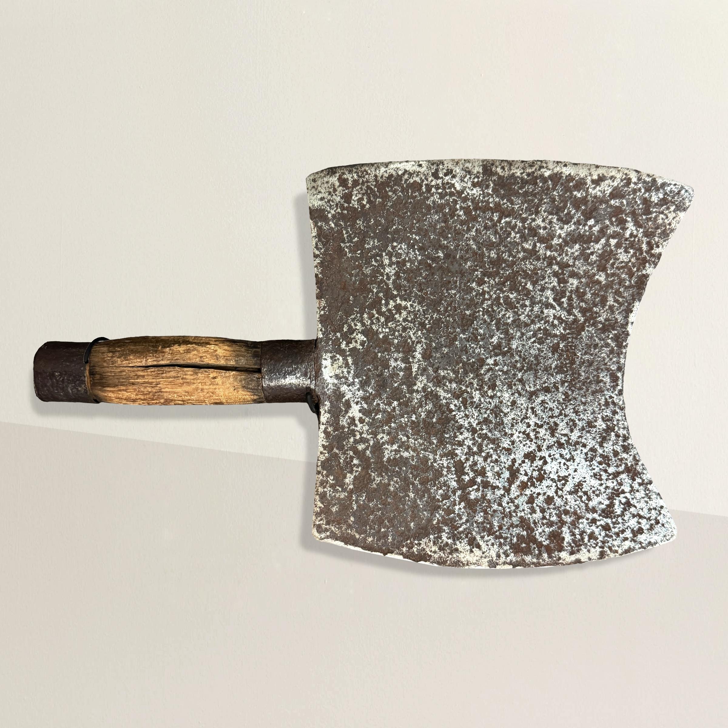 This 19th-century French butcher's cleaver is a striking relic from a time when craftsmanship and utility were intertwined. The double-edged blade, forged from iron, exudes the strength and durability needed for daily use in one of France's many