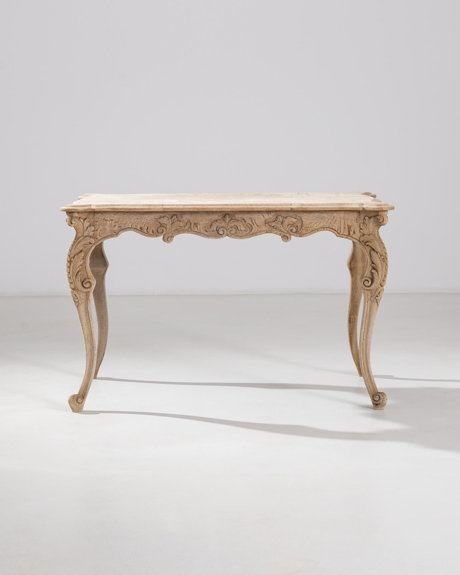 This oak table was produced in France, circa 1850. With a baroque inspiration, this piece displays a scalloped apron, intricately carved, and a curving cabriole leg. Adorned with carved foliage, scrolls and pearl-like dots meandering along the legs.
