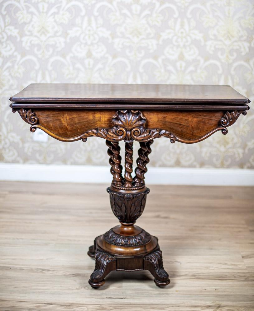 We present you a richly carved rosewood card table from third quarter of the 19th century.
The whole is placed on a striking pedestal composed of a square base on legs, round elements covered with carved patterns, and a bunch of spiral