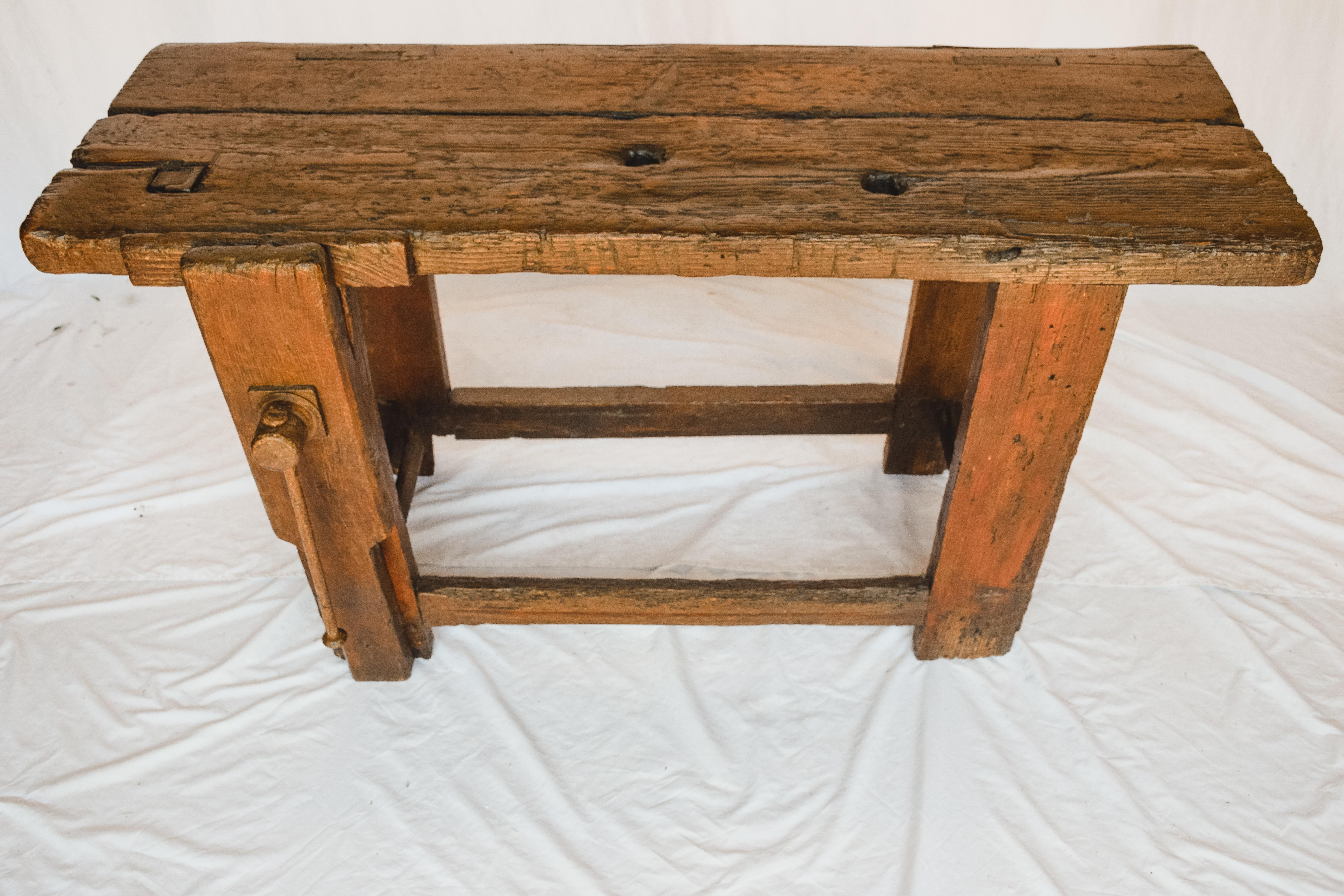 This beautiful 19th century workbench is made of solid wood and has a beautiful oak patina and original vise grip.  Originally used as a carpenter's workbench, the thick oak top sitting on sturdy square legs, shows its years of use.  Would be