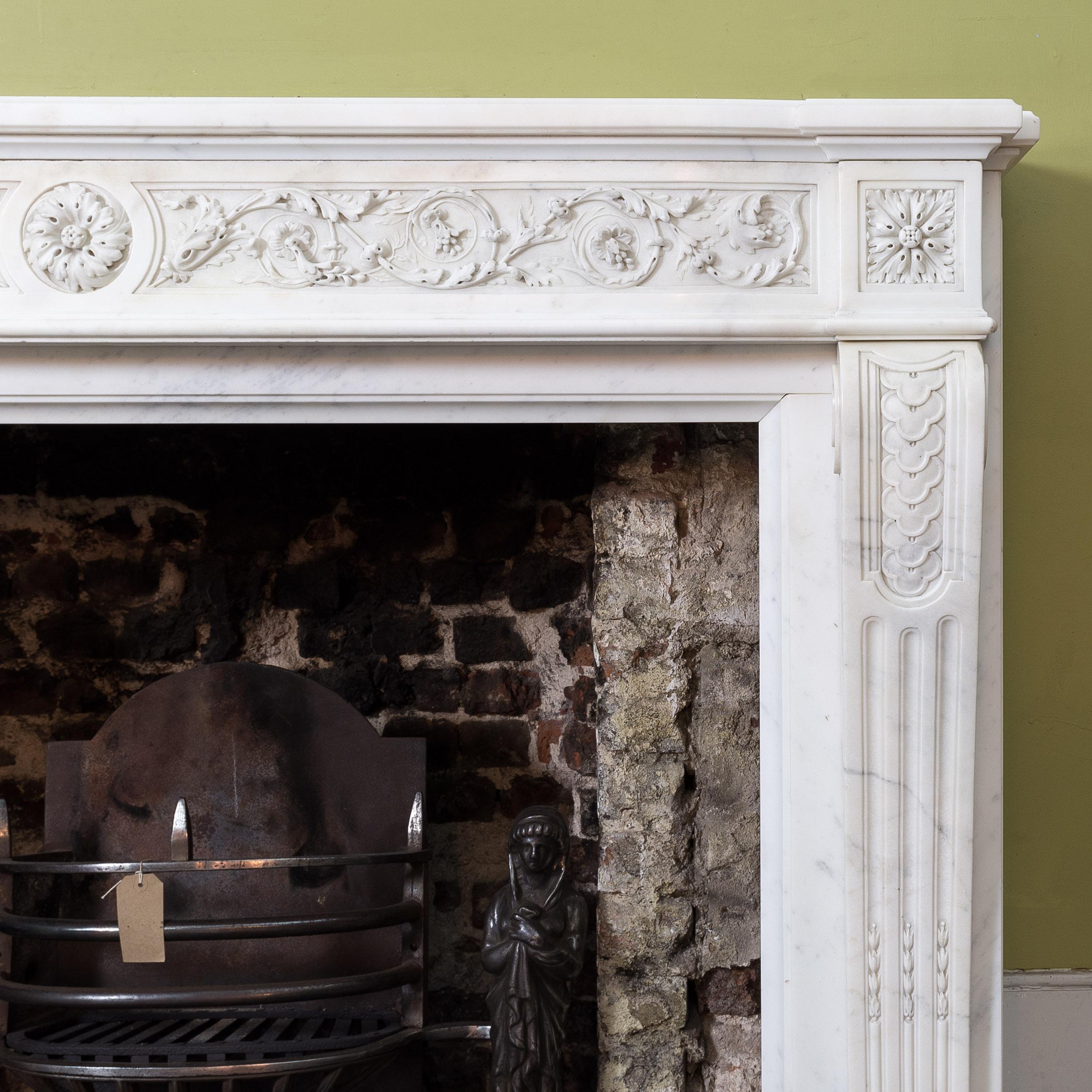 A good and well carved nineteenth century French marble fire surround, having a convex shaped shelf leading to a beautifully carved frieze of interlocking leaves, flowers and scrolls, flanked by patera corbel blocks, above scrolled jambs decorated