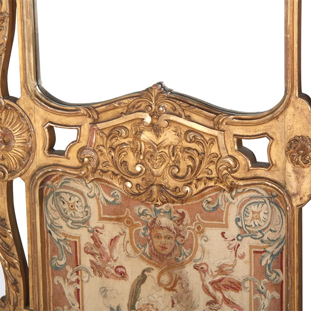 A 19th century highly-detailed French carved gilt-framed three-panel screen embellished throughout with carved foliage, swags, faces etc, the lower panels with inset Aubusson tapestries, the upper panels with mirrors.

 
