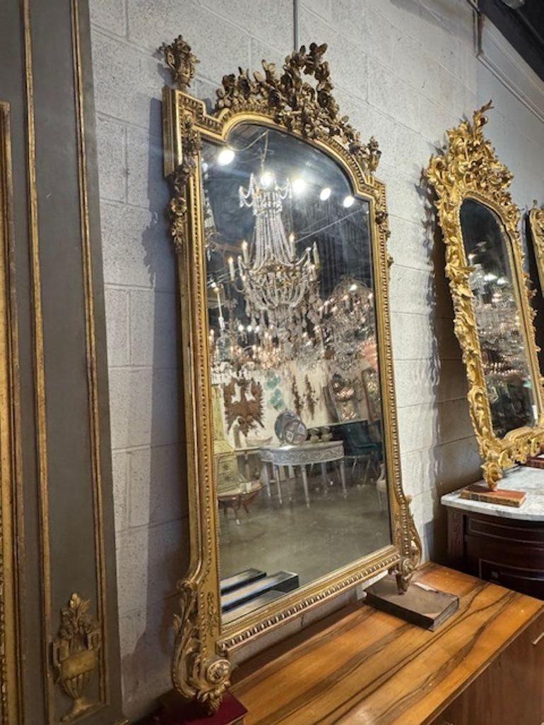 El Espejo Luis XVI francés tallado y de madera dorada del siglo XIX es una lujosa y elegante pieza de decoración para el hogar que destila sofisticación y estilo. Con intrincados detalles tallados a mano y un llamativo acabado en madera dorada, este