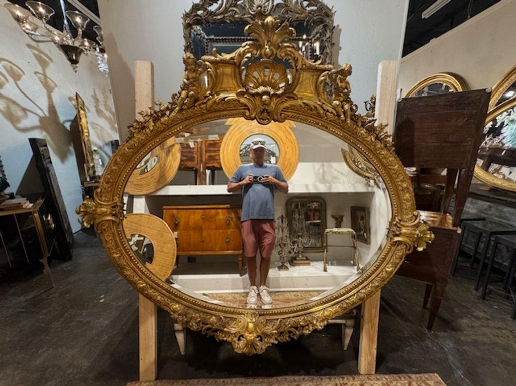 Elaborato specchio francese di grandi dimensioni in legno intagliato e dorato. Caratterizzato da un bellissimo stemma e da due putti nella parte superiore dello specchio. Un pezzo eccezionale!
