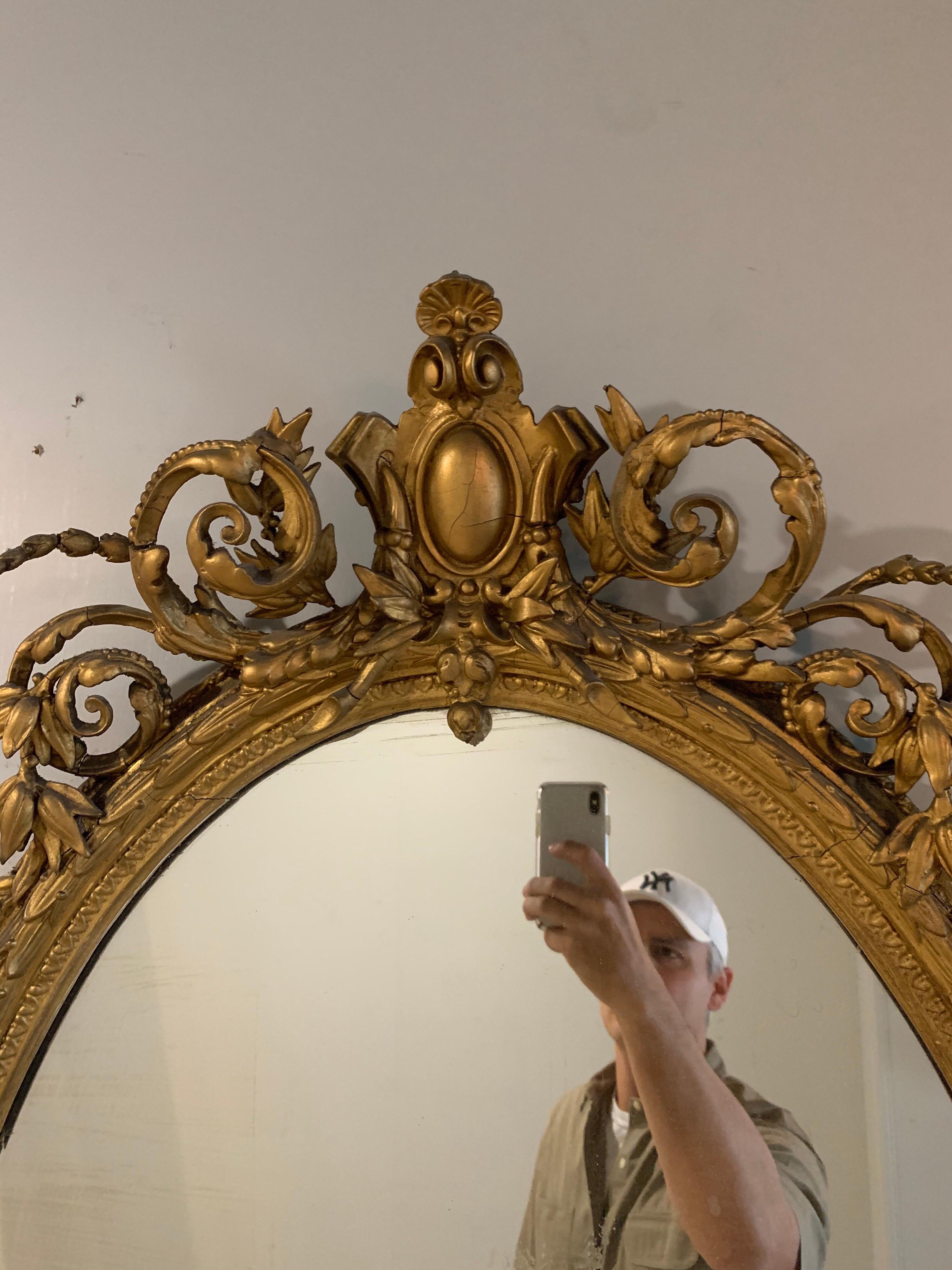 Delizioso specchio ovale in legno dorato francese del XIX secolo con splendidi intagli. Questo pezzo ha un'applique a tre bracci nella parte inferiore dello specchio. Davvero unico!