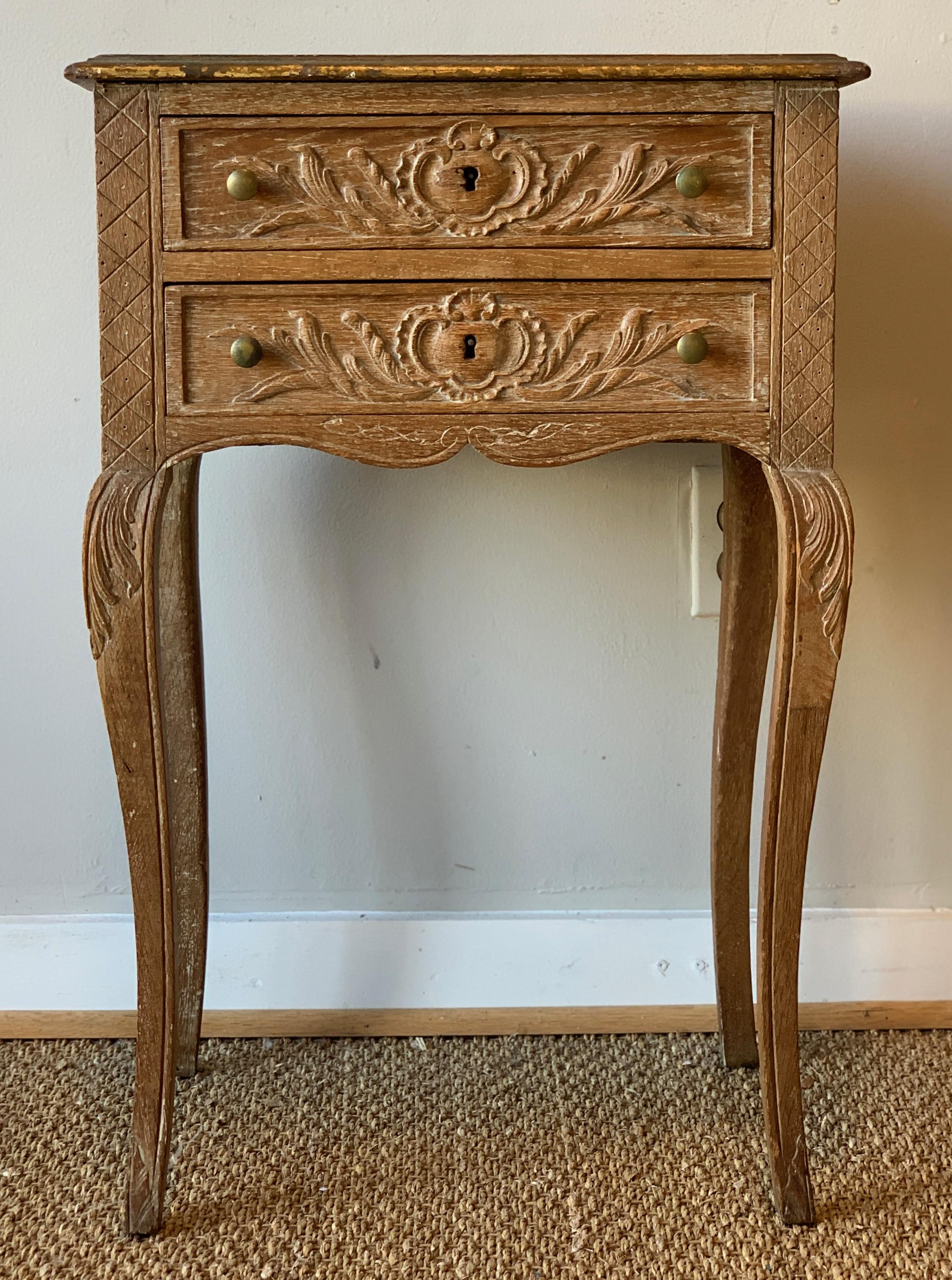 Charming small scale and beautifully carved and limed oak two-drawer side table with traces of old gilt decoration.