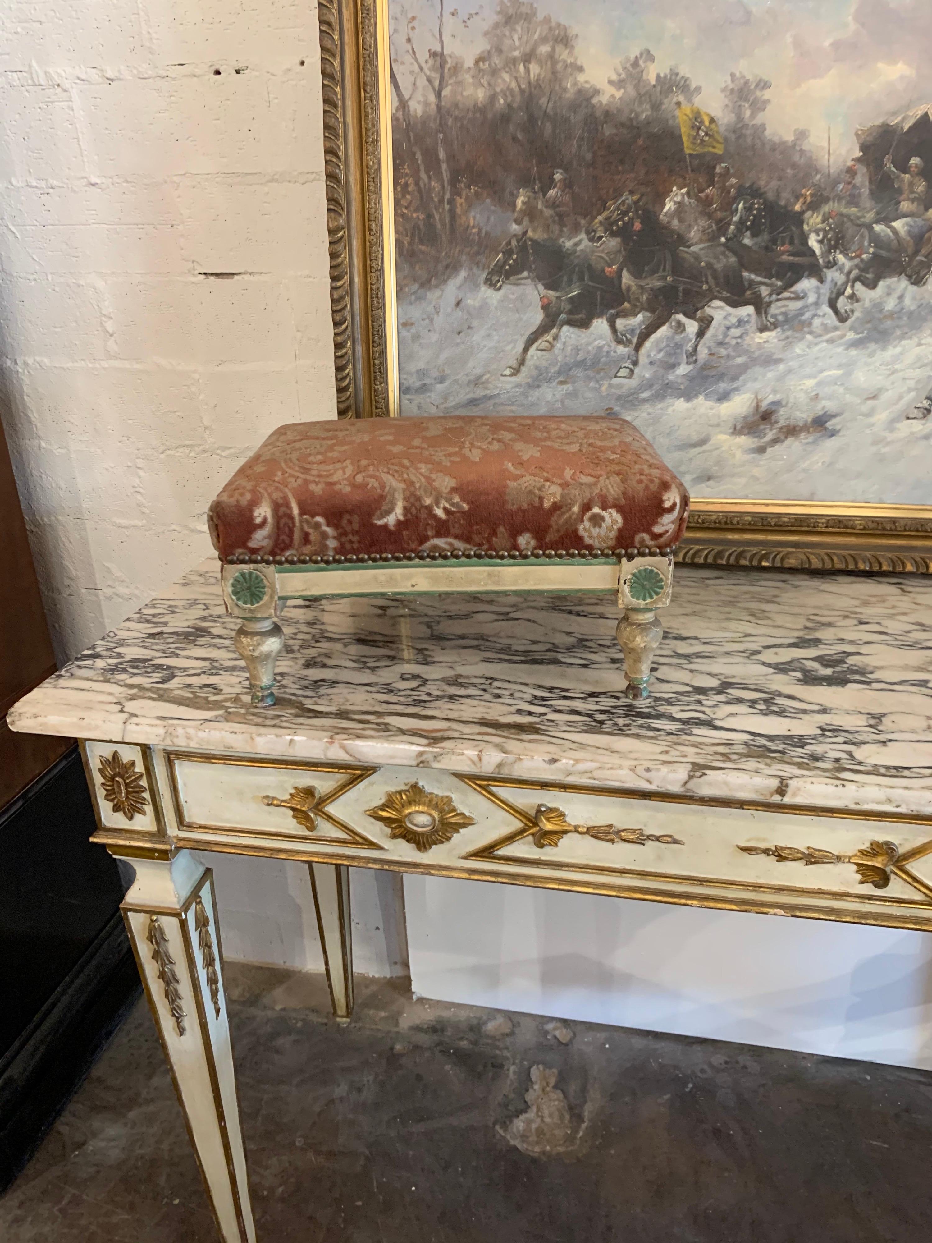 Decorative 19th century French carved and painted Directoire' style foot stool. Upholstered in a beautiful rust colored floral fabric. A very fine accessory!