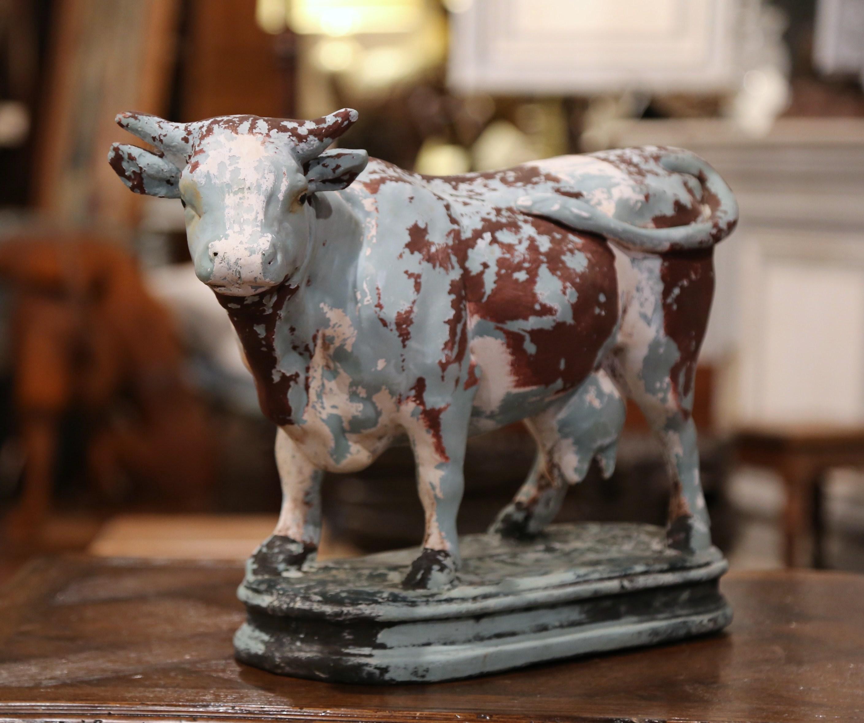This antique bovine sculpture was crafted in Normandy, France circa 1880, standing on an oval base, the cow made of carved papier mâché, features the original multi-color hand painted finish in the pale blue, white and brown palette. The sculpture