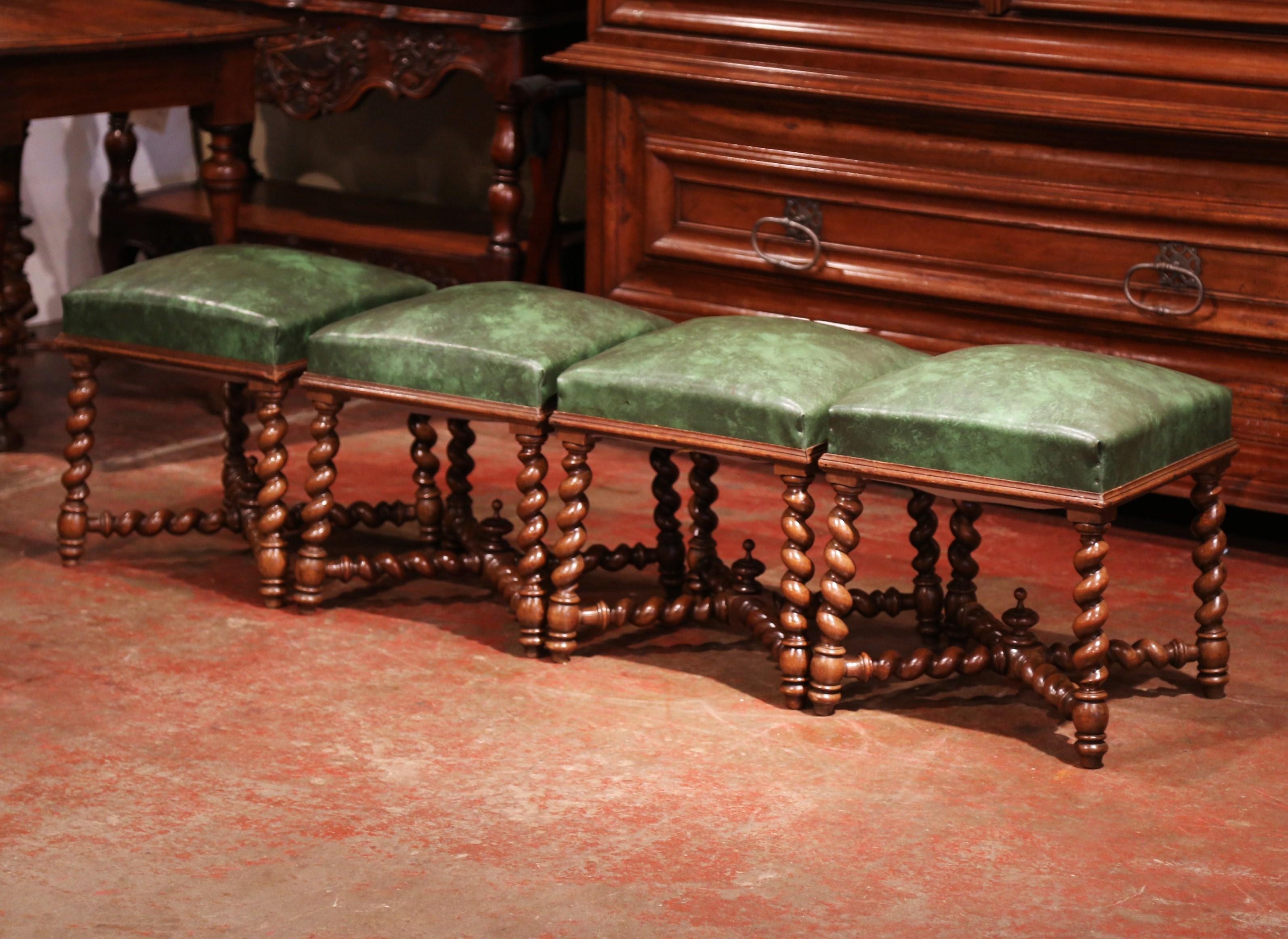 Crafted in France, circa 1860, each antique stool is square in shape and features four slant barley twist legs with matching stretcher and a decorative, carved central finial. Each Baroque, Louis XIII seat has been recovered with a patinated green
