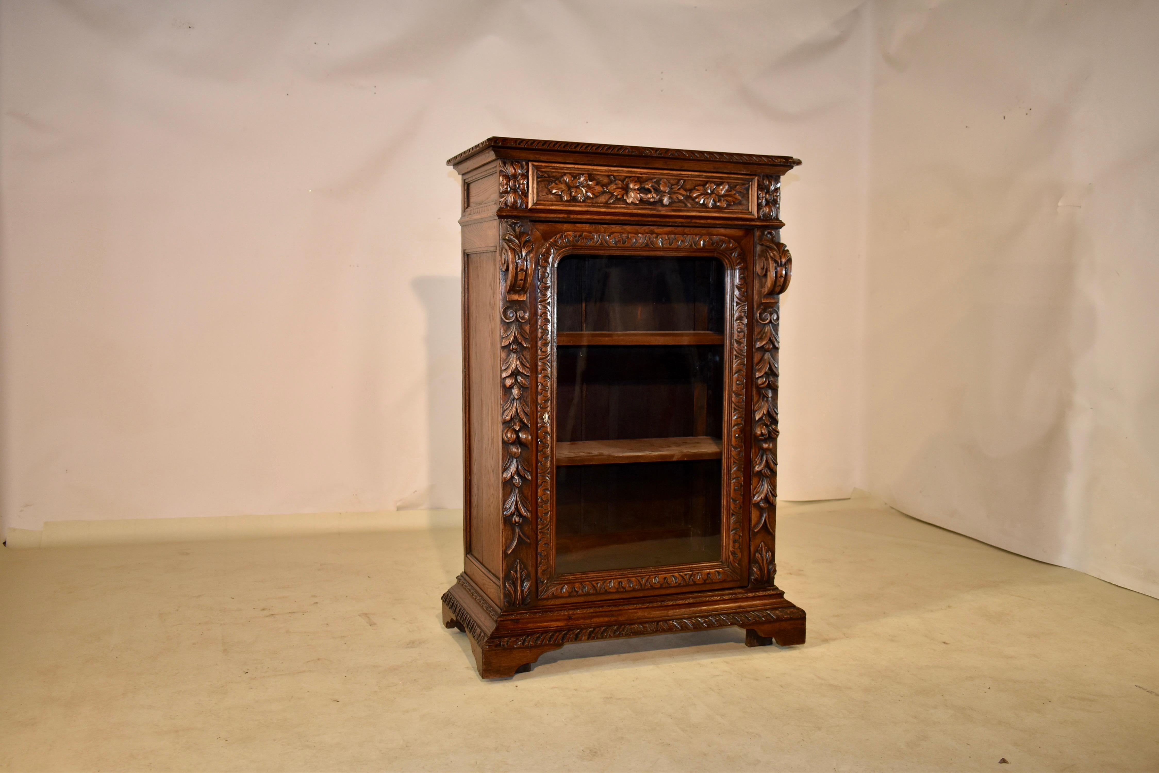 19th century oak hand-carved bookcase from France. The top is banded and has a beveled and hand carved edge, following down to paneled sides and a single drawer in the front, with a hand carved decorated drawer front and hand carved handle, which is
