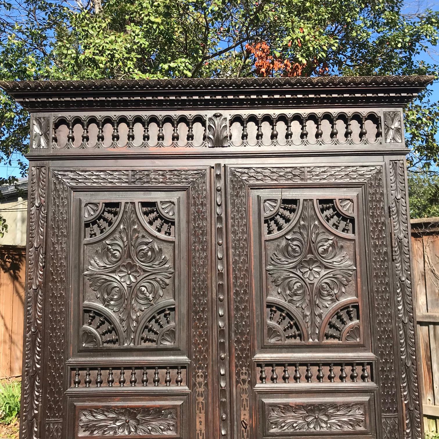 Decorate a den or a bedroom with this elegant antique armoire. Crafted in Brittany, France circa 1860, the fruitwood cabinet stands on bun feet and features two heavily carved doors across the front, two drawers at the bottom embellished with iron