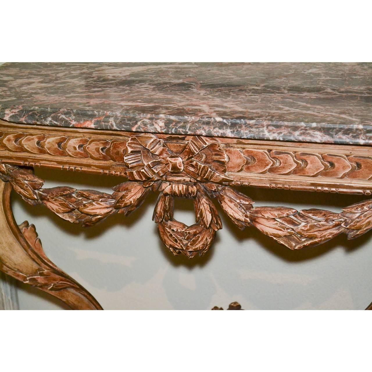 Add instant elegance to any interior with this gorgeous 19th century French lacquered wood console table with a particularly fine heavily veined marble top. The base all hand-carved with knotted bows and thistle swags. The graceful contoured legs