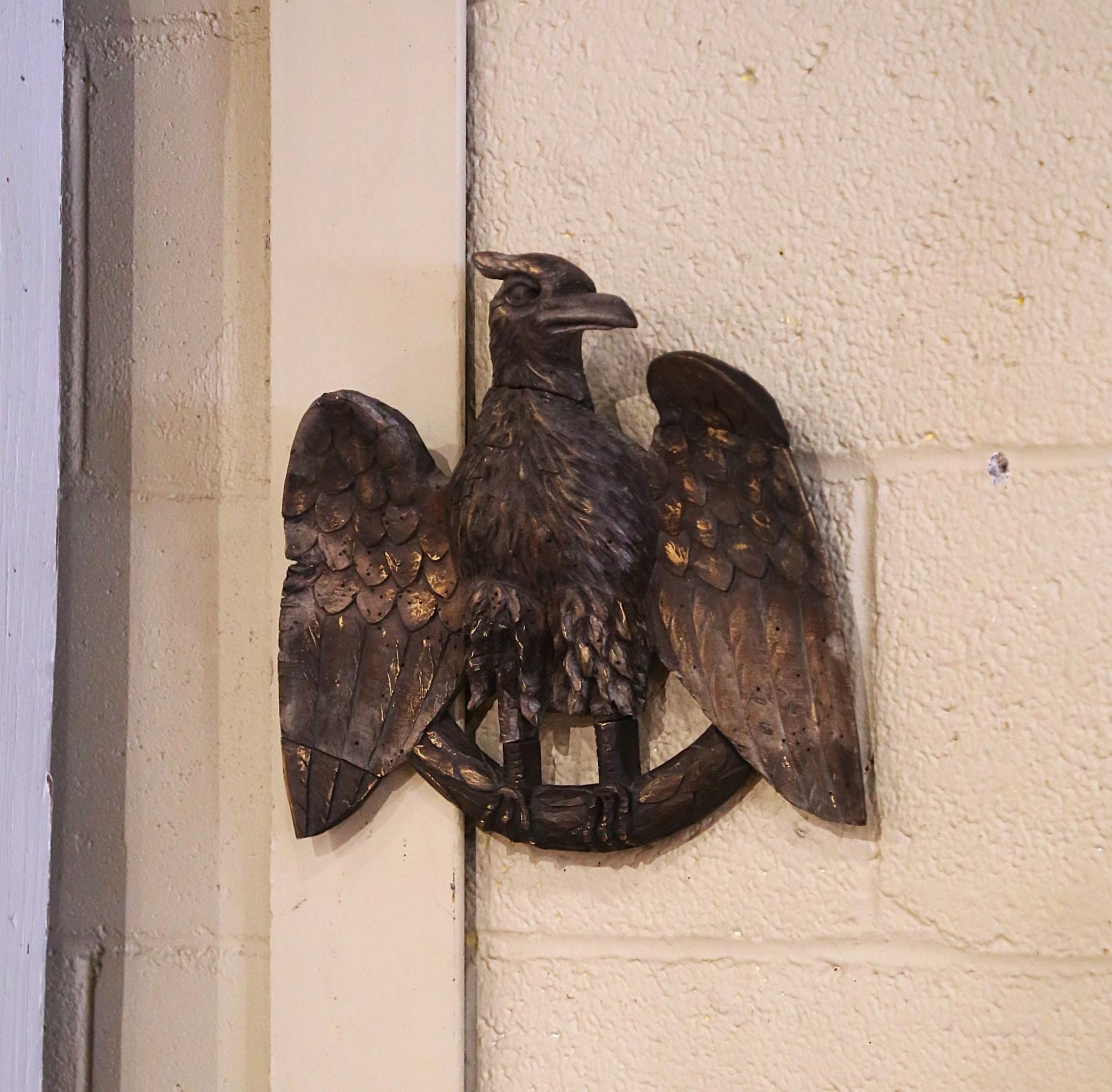 This regal antique eagle wall sculpture was crafted in France, circa 1880. The hand carved eagle features an imposing stance, with its wings spread wide open and its talons gripping a branch. The carving is detailed, with individually defined