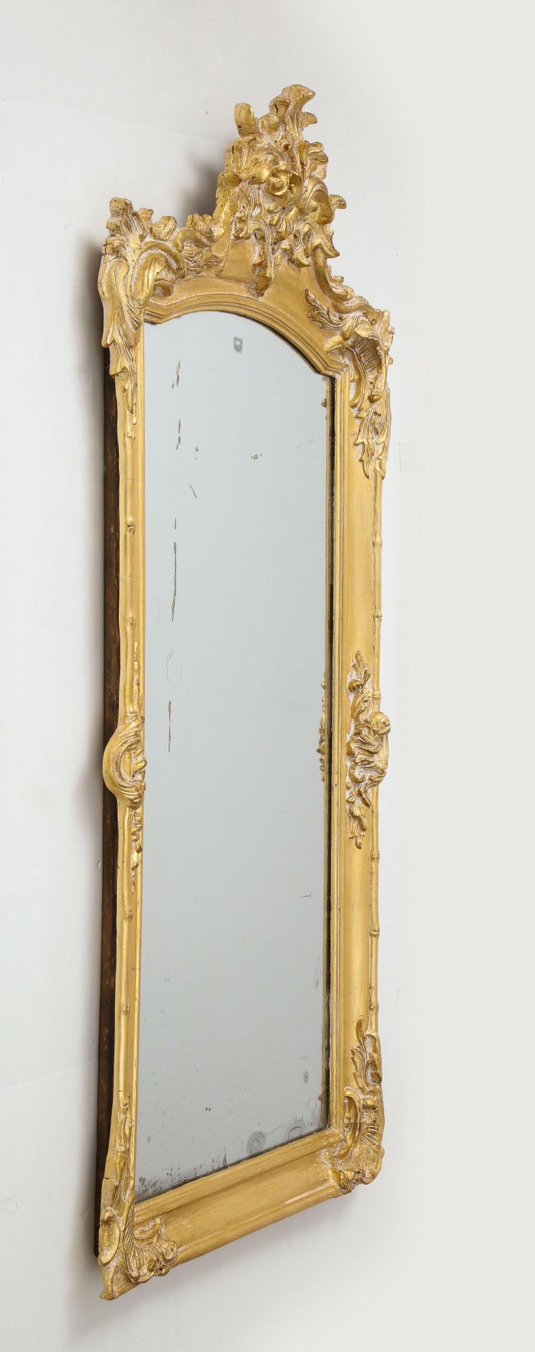 Fanciful French 19th century carved and gilded framed mirror depting stylized bamboo and leaf motif. Original aged mercury glass mirror inset.