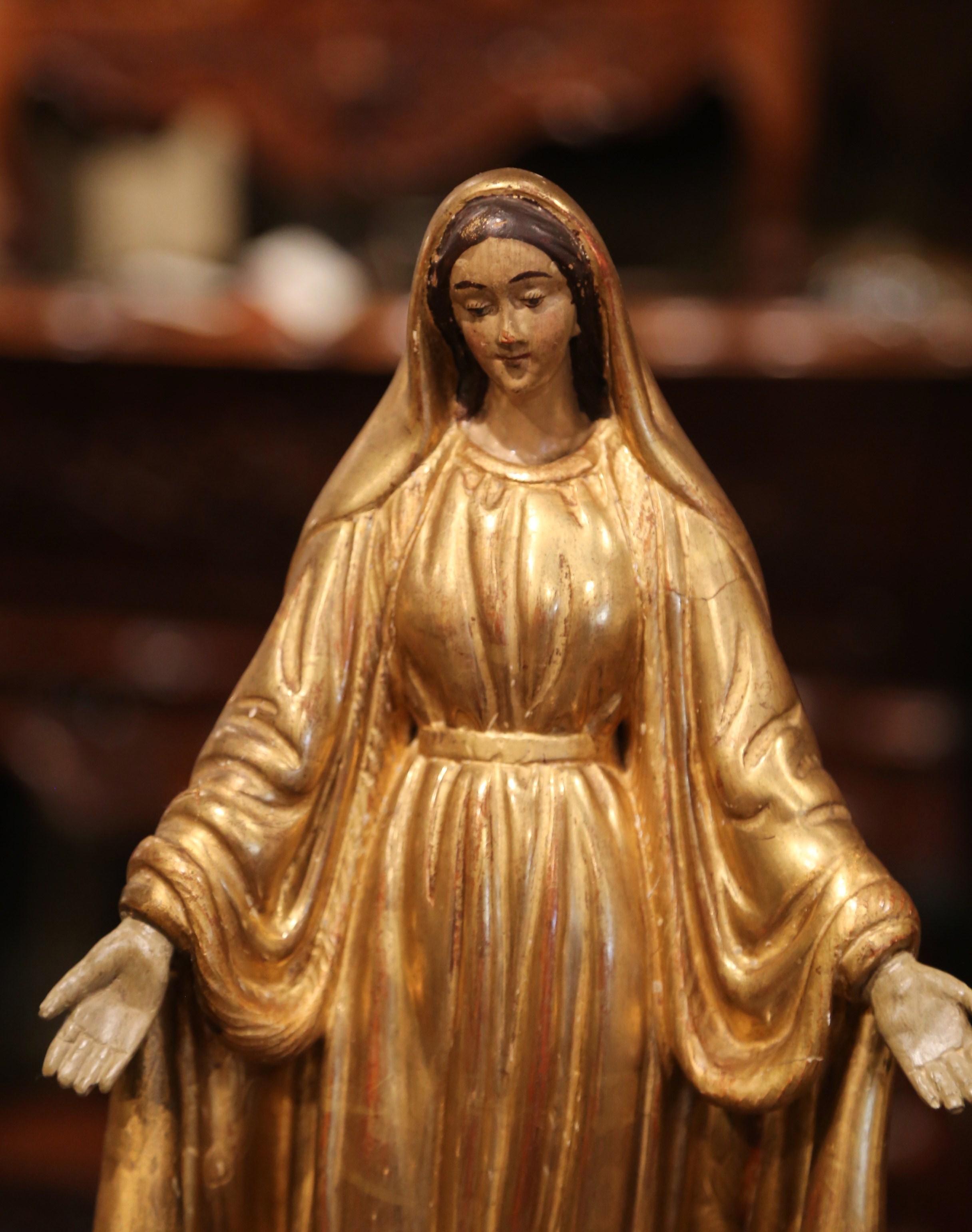 This beautiful, antique sculpture of the Virgin Mary in prayers was created in Provence, France, circa 1860. Embellished with gold leaf and polychrome finish, including discrete engraved floral motifs, the Classic religious figure is beautifully