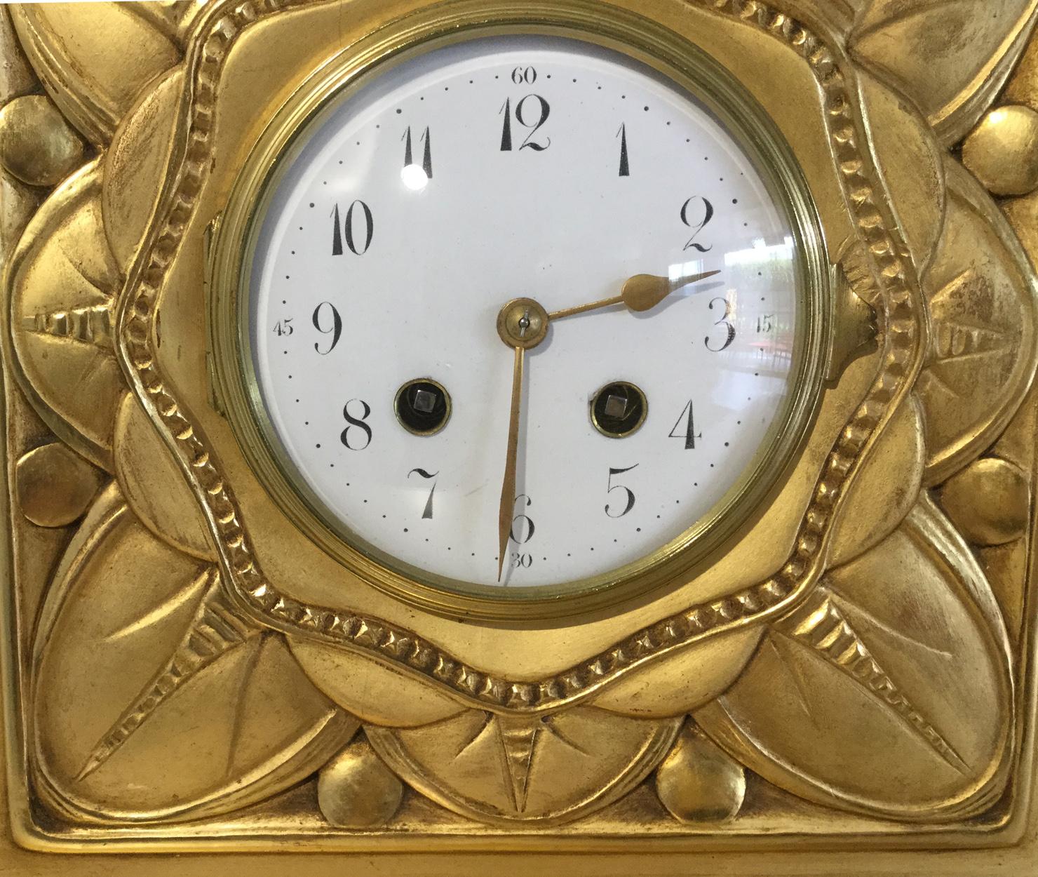 A decorative late 19th century French carved giltwood cased mantel clock with eight day movement striking the hours and half hours on a bell, the circular enamel dial with Arabic numerals, the rectangular case with carved foliate pattern to the