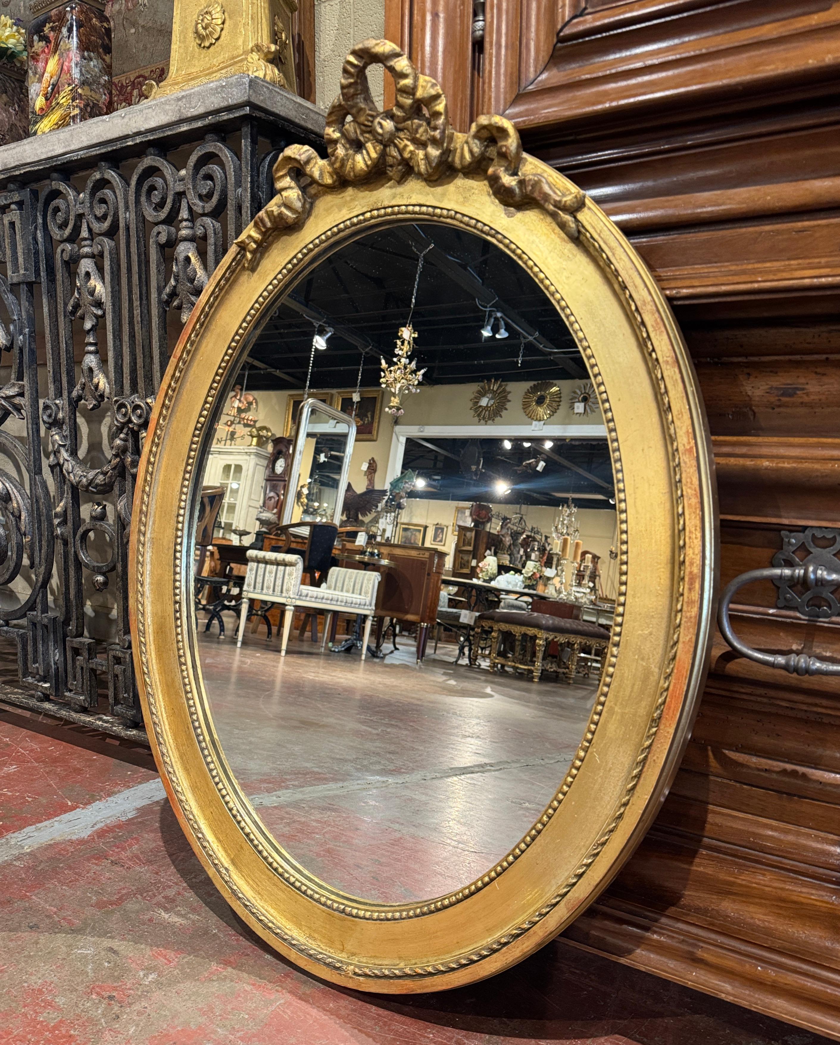 Eleganza e stile: questo elegante specchio da parete dorato e antico è ideale per arredare la stanza della toilette o l'ingresso. Realizzata in Francia, intorno al 1880, e di forma ovale, la cornice è vestita con il tradizionale fiocco traforato