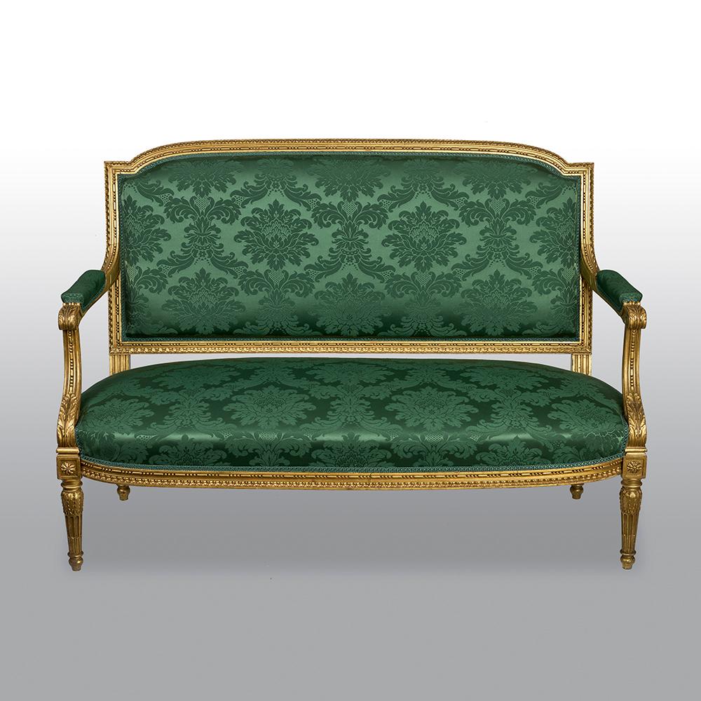 A five piece French Louis XVI style giltwood carved Salon 'Parlor' Suite. The carved gilded wood frame with a floral design and leaves, with padded open armrests and raised on four fluted legs, all upholstered in a green silk, Paris, circa