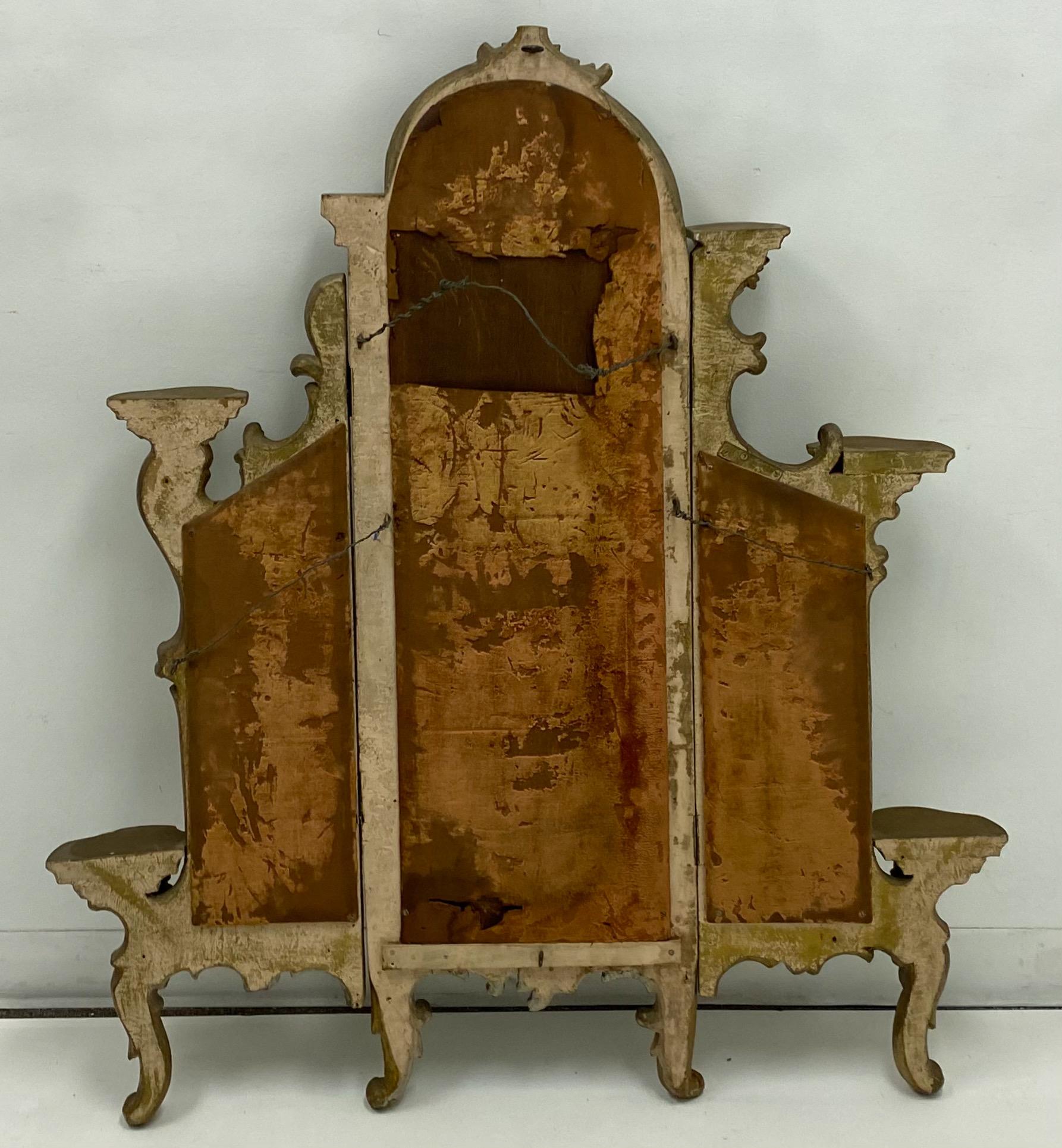 J'adore ça ! Il s'agit d'un miroir triptyque en bois doré sculpté du 19ème siècle. Bien qu'il ait été adapté pour être fixé au mur, il a probablement été posé sur une commode à un moment donné. Le miroir comporte huit petites étagères encadrant la