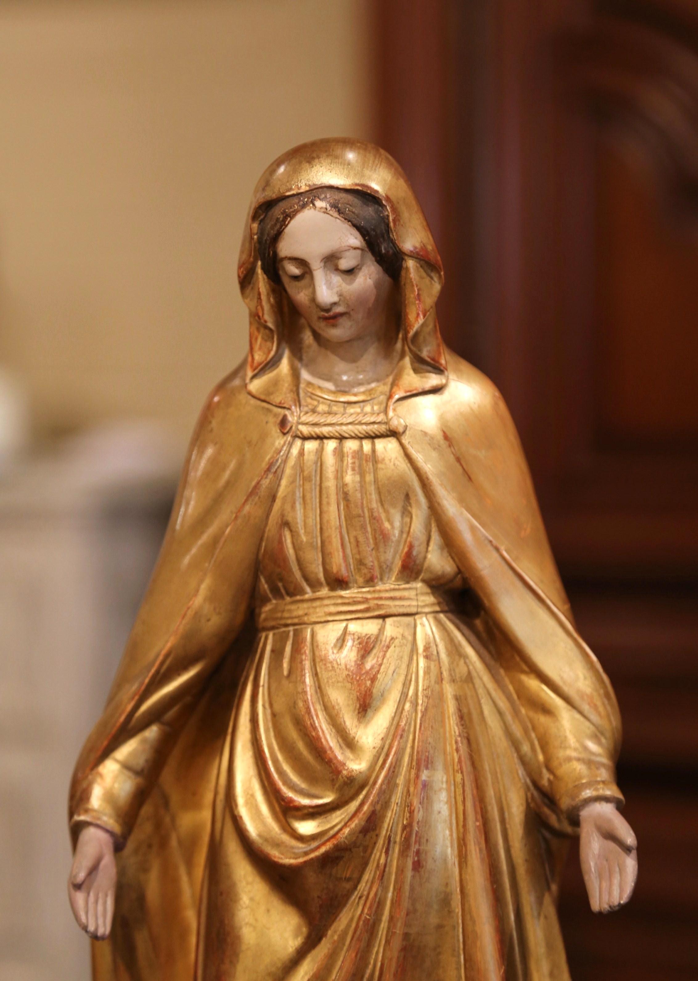 This beautiful, antique sculpture of the Virgin Mary in prayers was created in Provence, France, circa 1860. Embellished with gold leaf and polychrome finish, including discrete engraved floral motifs, the Classic religious figure is beautifully