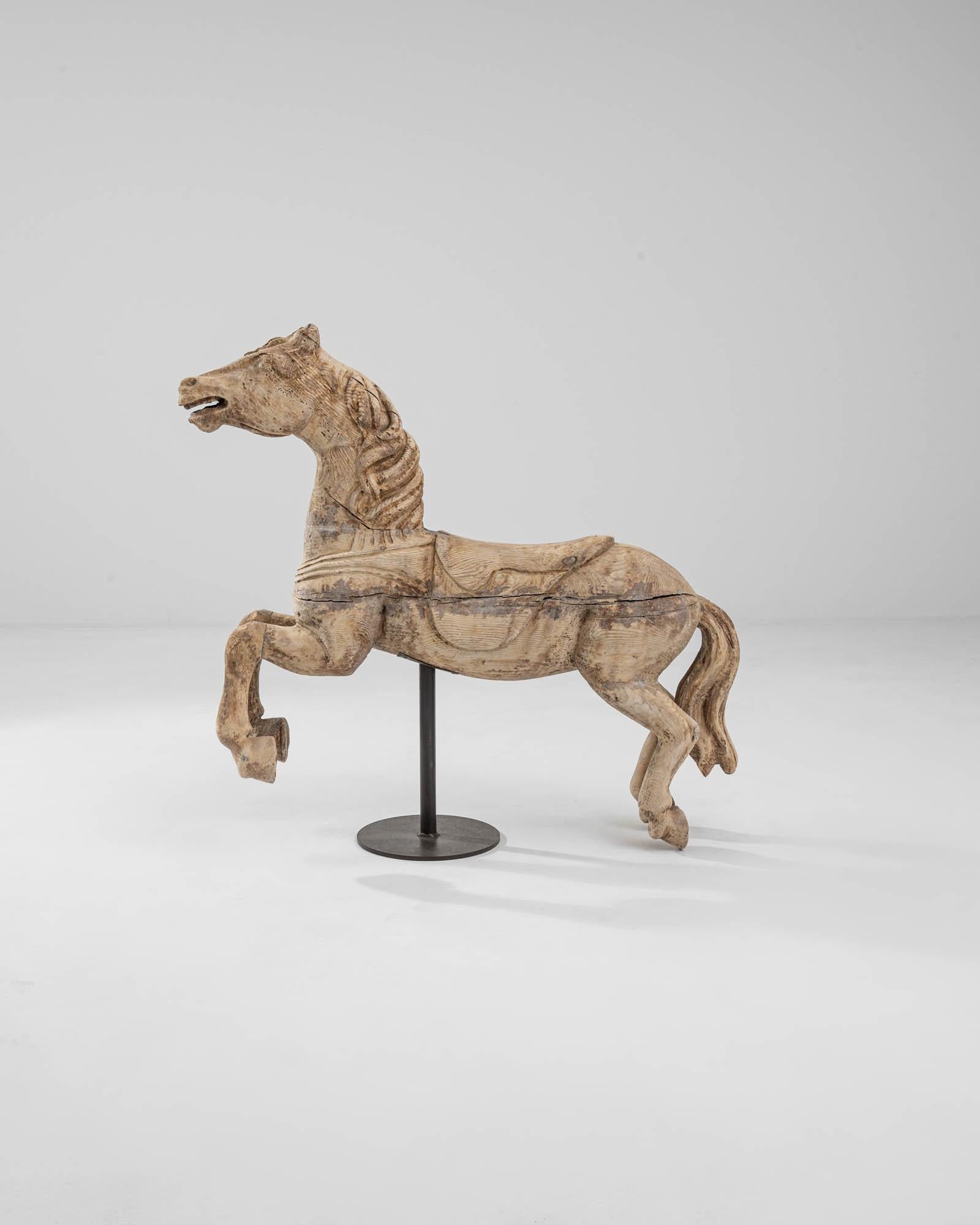 A wooden sculpture of a horse from 19th century France. Captured mid-gallop, this bounding horse vibrates with charismatic energy. The grain of the wood runs like striae of hair along its body, creating the sensation of the wind blowing through it.