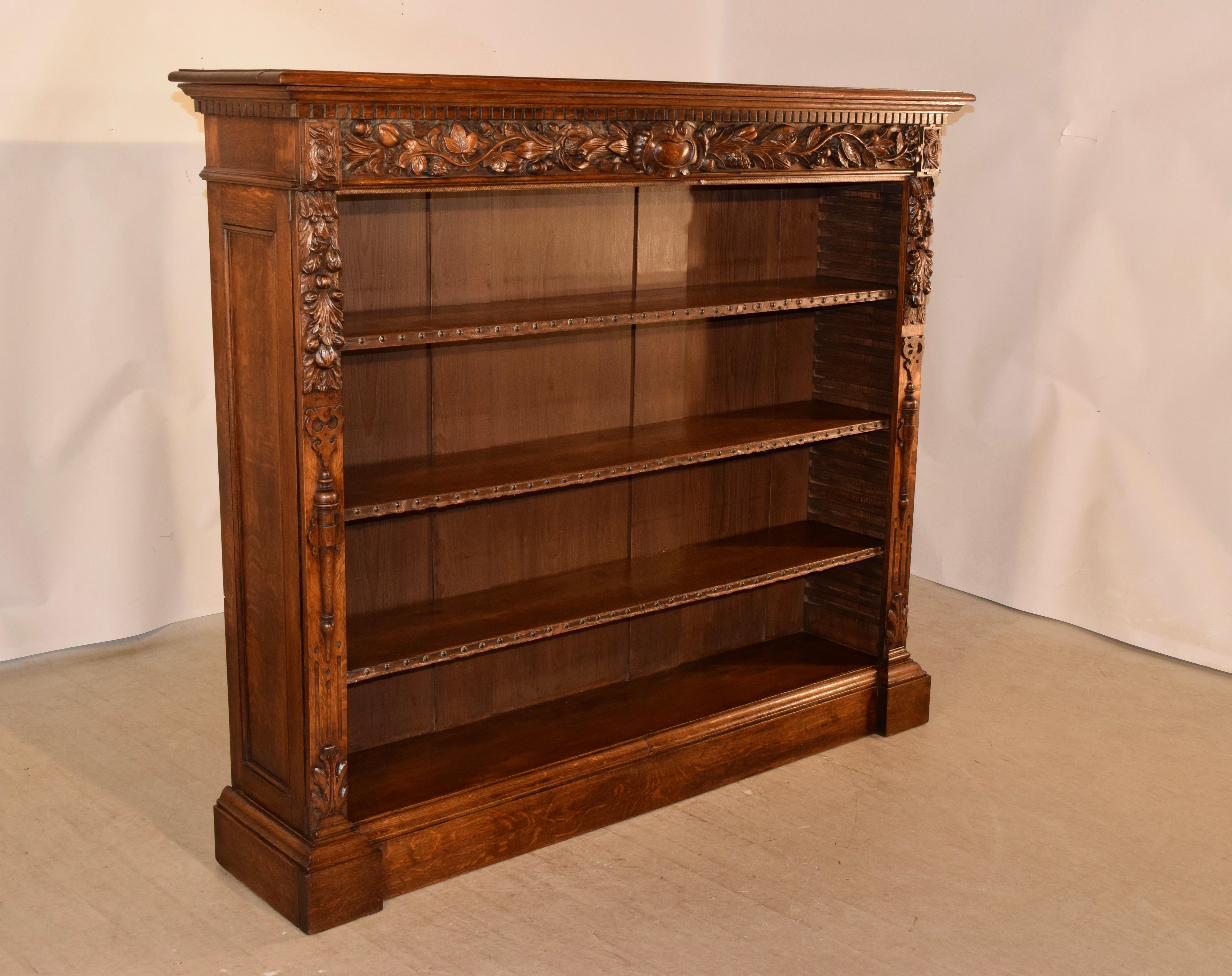 19th century wonderfully hand carved oak bookcase from France. The top has a beveled edge, following down to a highly detailed hand carved apron depicting a central cartouche flanked by floral and leaf decoration, and hand carved decorated columns
