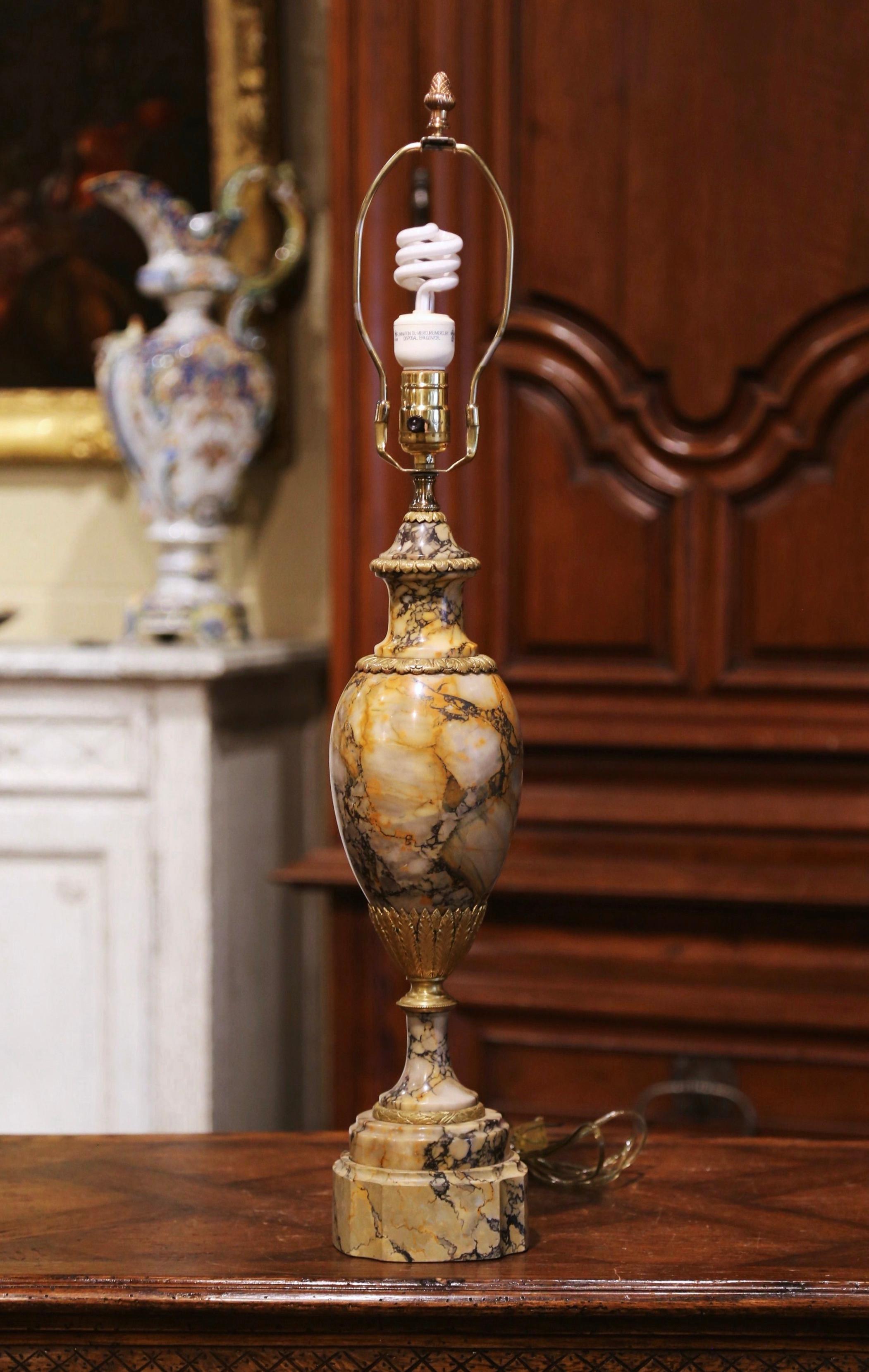 Dress a office desk or study with this elegant antique table lamp. Crafted in France, circa 1870, the tall lamp shaped as an urn, stands on a round base decorated with bronze mounts and leaf motifs. The large, carved cassolette lamp made of