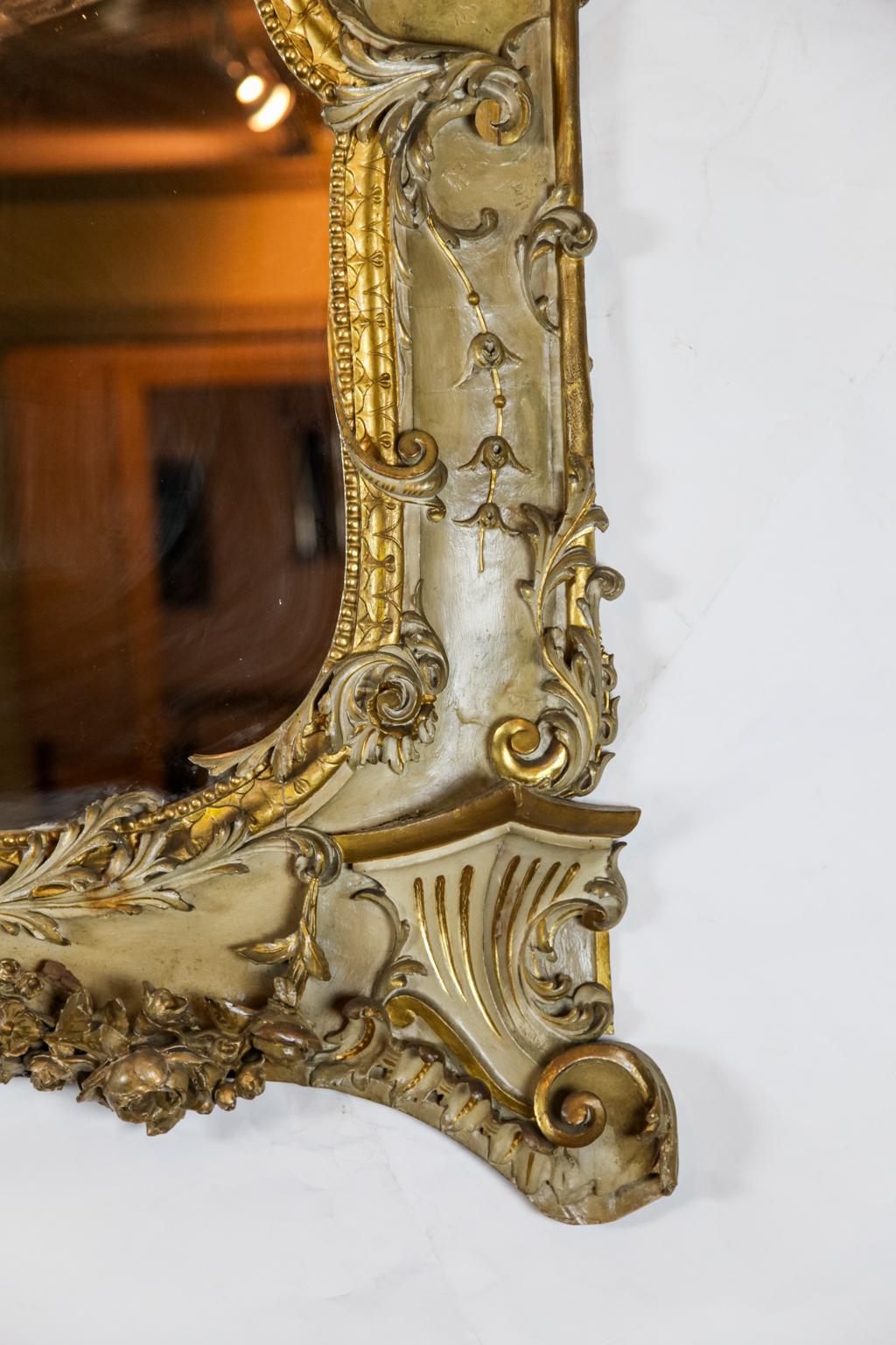 19th century French carved mirror, the horizontal mirror surrounded by carved arabesques and foliate in relief, with central stylized central shell motif, gilded accenting throughout.