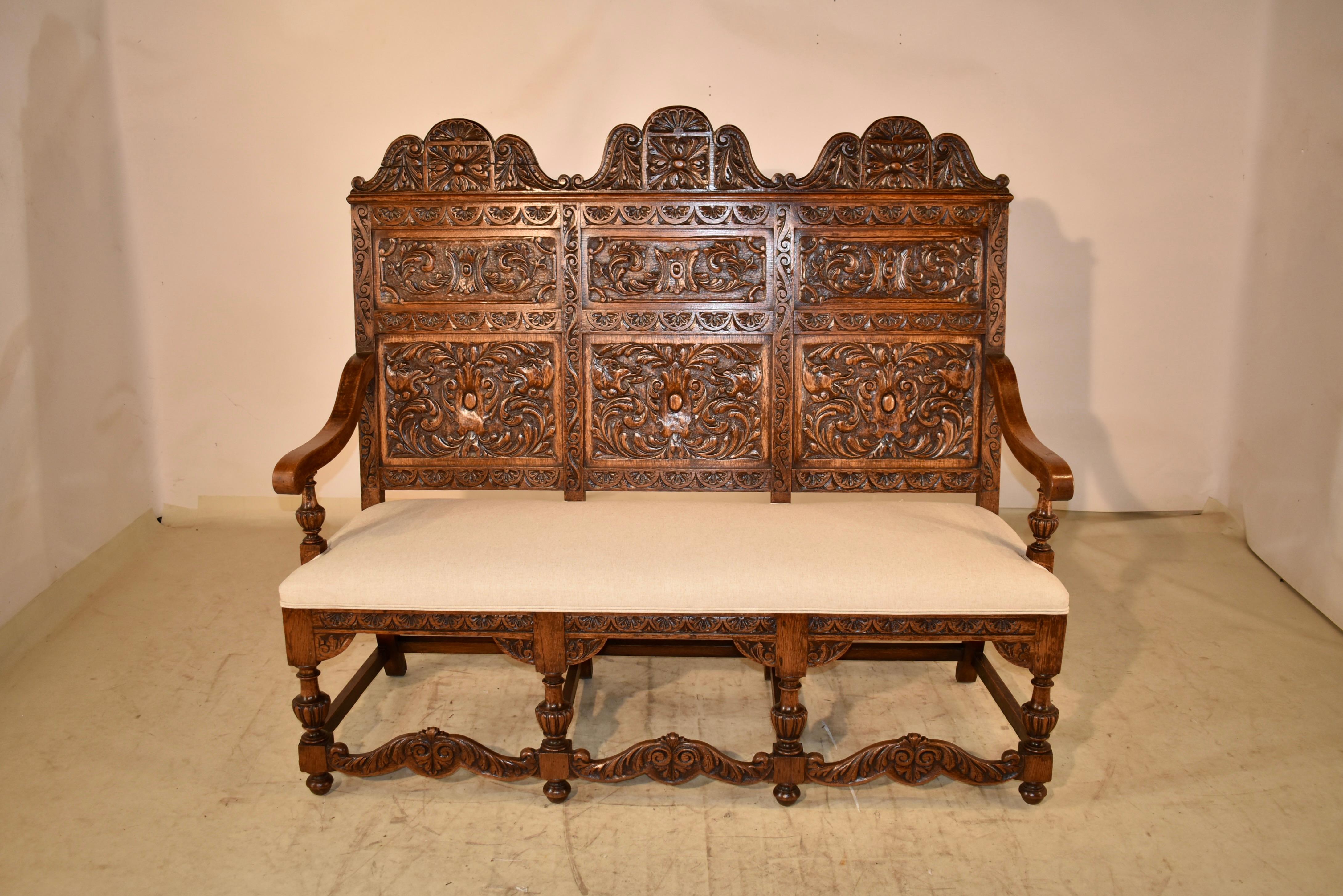 19th century oak bench from France with the most glorious hand carved decoration we have had the privilege to offer.  The back of the bench is wonderfully tall, and has three panels, all with exquisite hand carved decoration, separated by hand